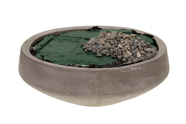 Line the concrete container, fill it with floral foam, and cover part of it with pea gravel.