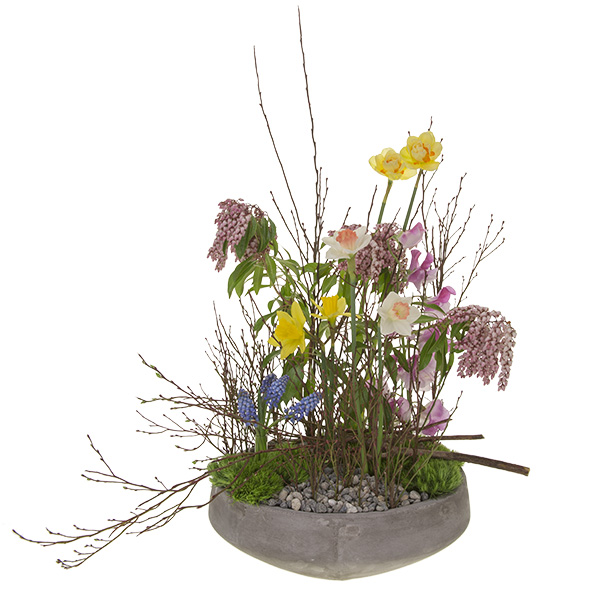 This spectacular floral design in the vegetative style features spring flowers like muscari, daffodils, and sweet peas with green trick dianthus, andromeda, and budding huckleberry branches.
