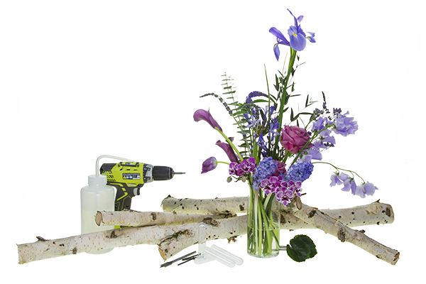 materials and tools for the project, including flowers, branched, water tubes and an electric drill