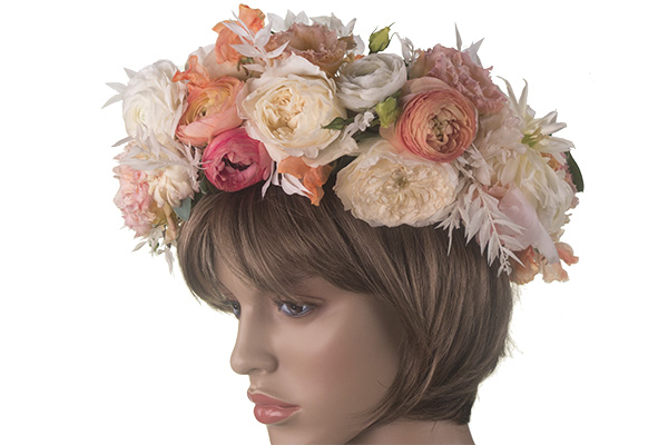 A beautiful floral crown in peach hues mixes garden roses, ranunculus, and other beautiful blooms for a lovely effect.