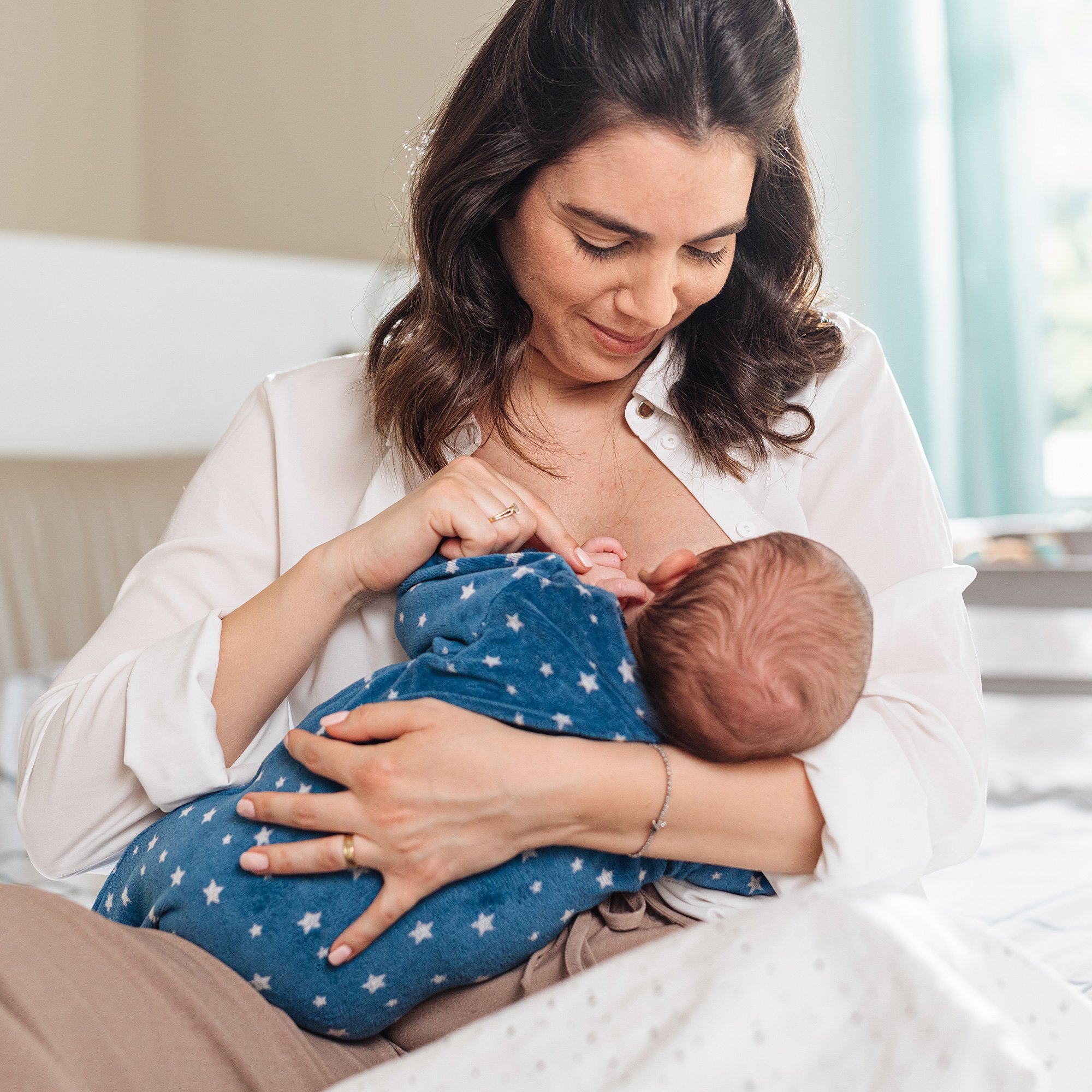 mom breastfeeding baby in bedroom