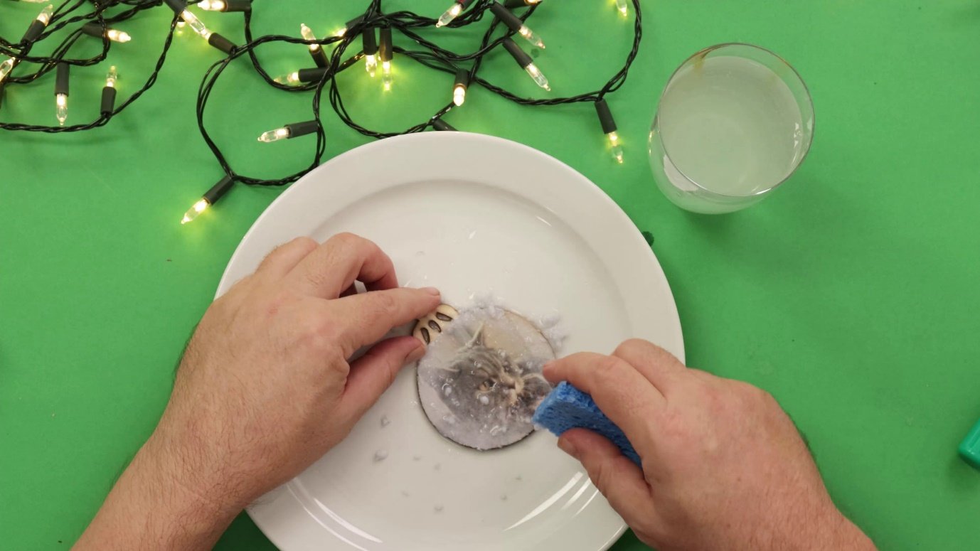 A person cleaning a plate with a blue spongeDescription automatically generated