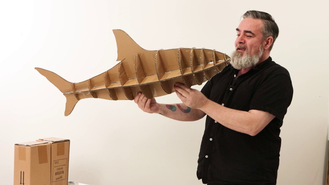 A person holding a cardboard sharkAI-generated content may be incorrect.