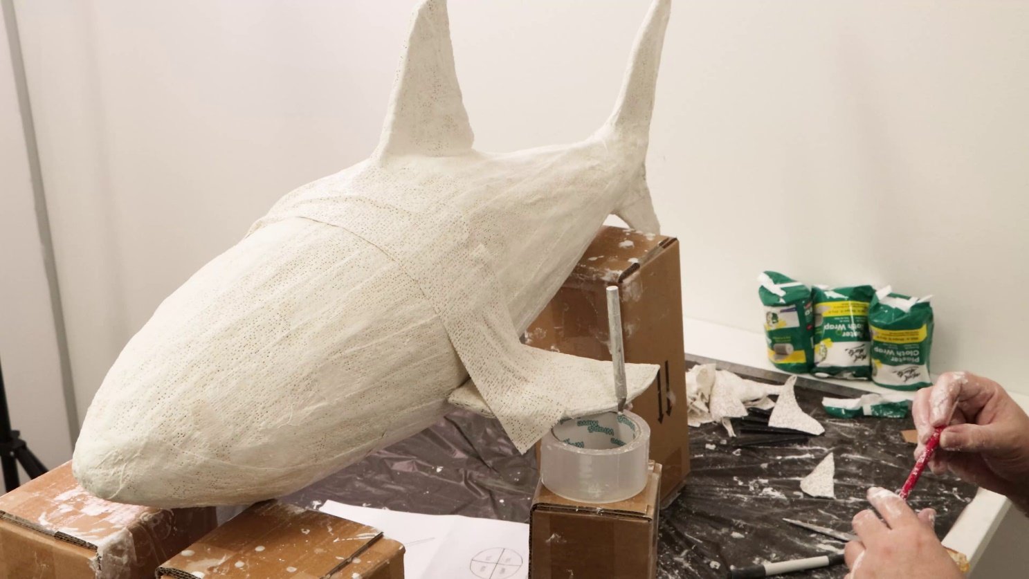 A shark sculpture being paintedAI-generated content may be incorrect.