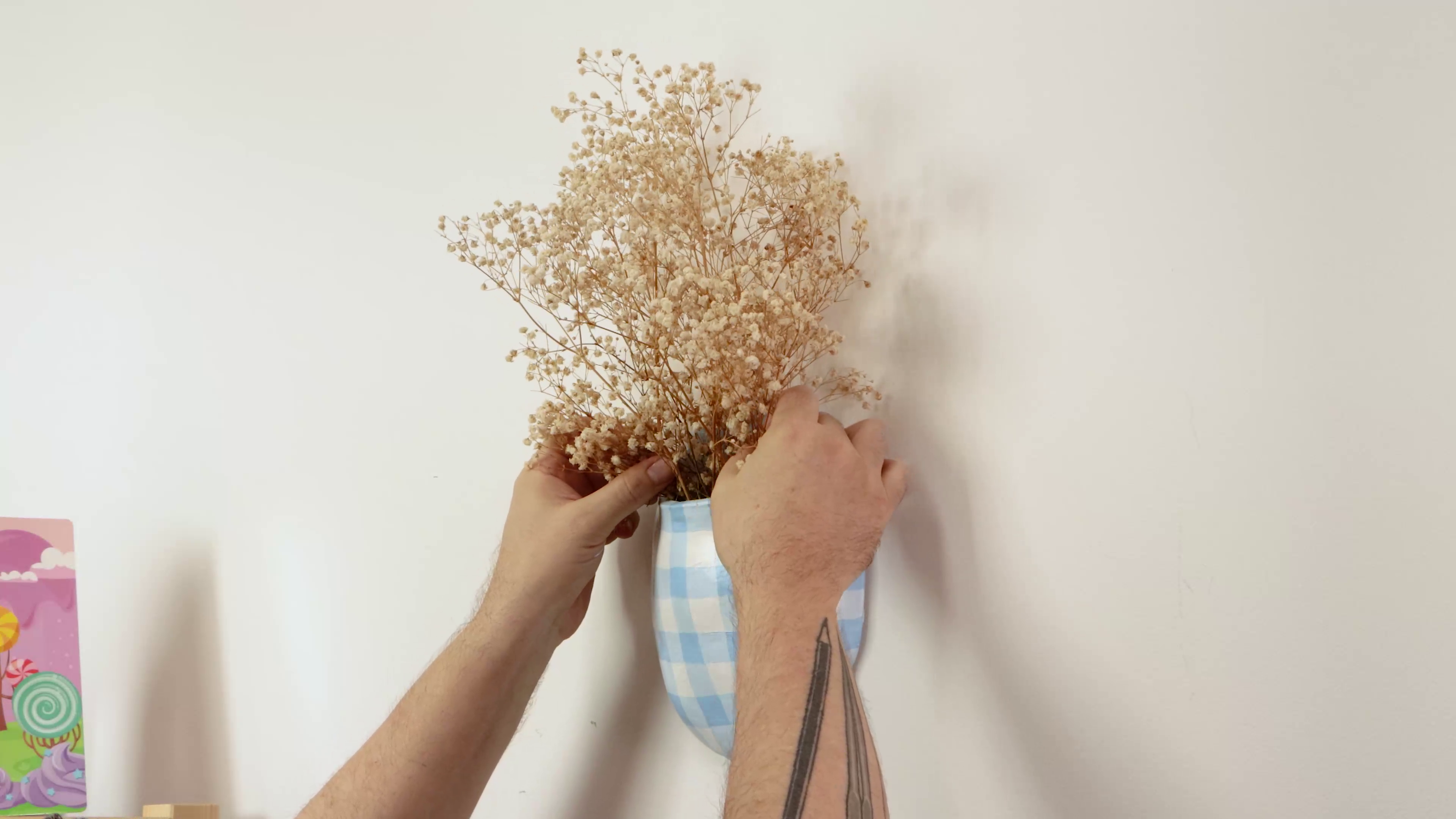 Placing dried flowers into gingham clay vase