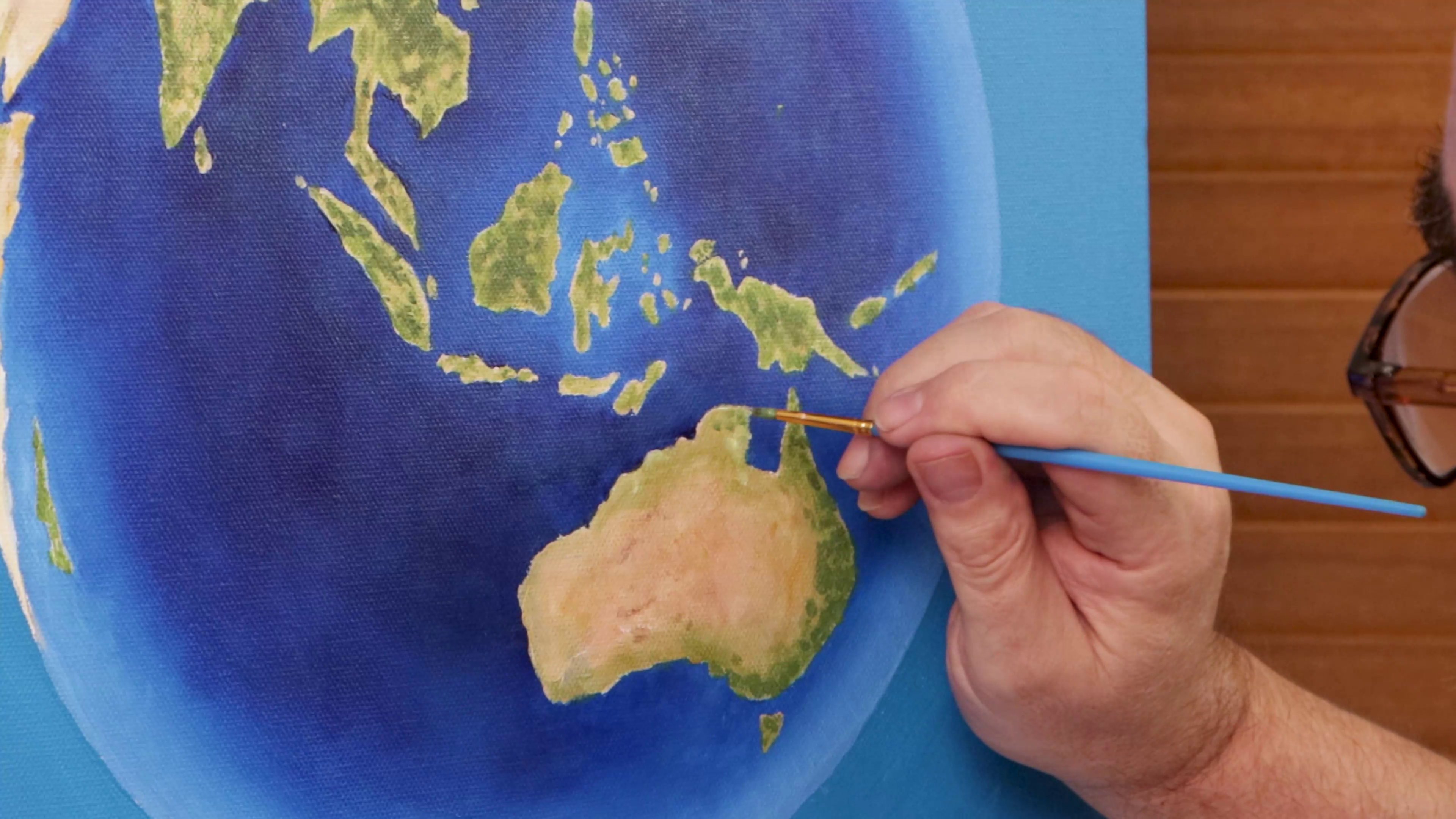 Dappling green paint onto Australia on earth artwork