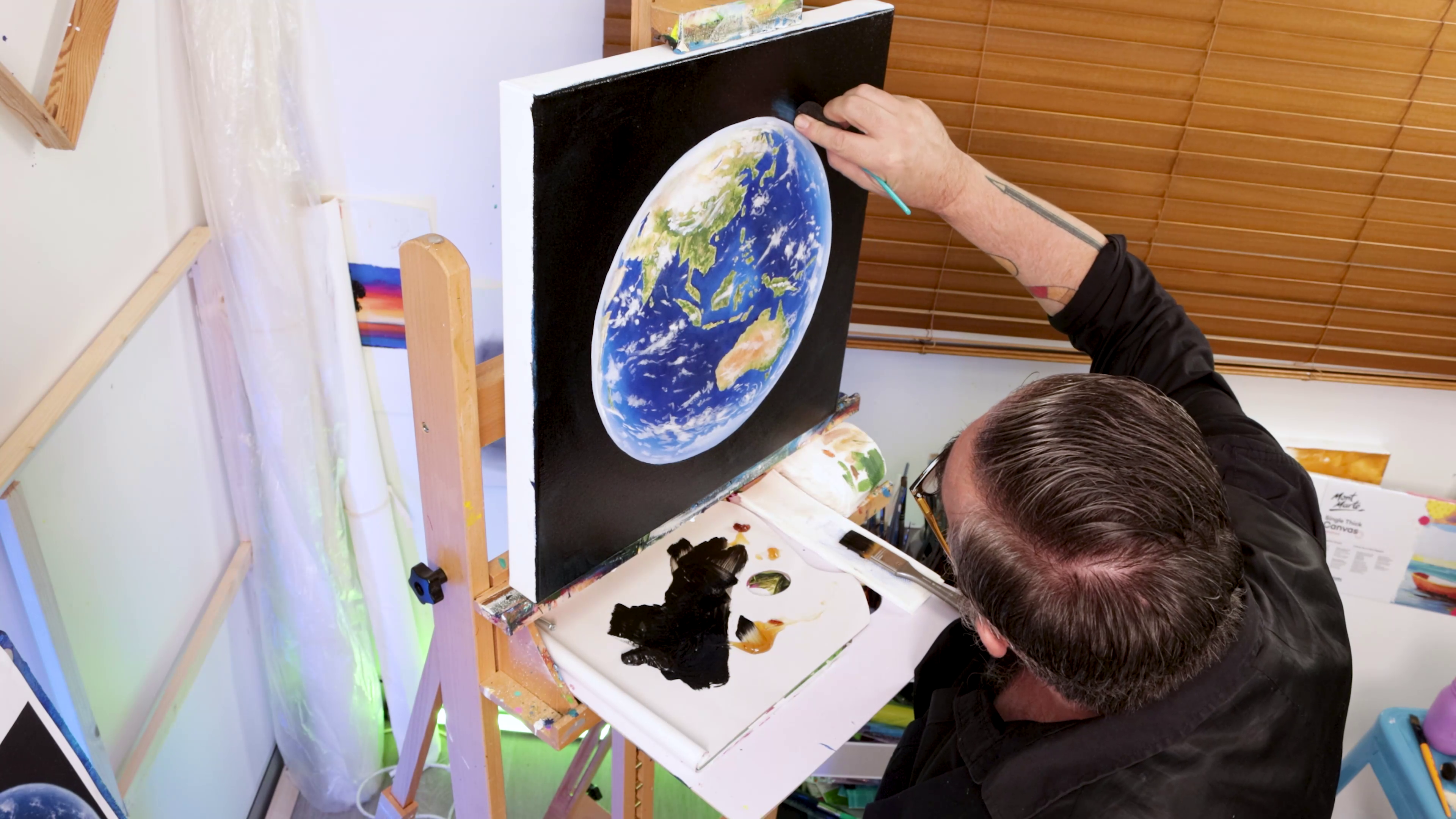 Painting black background around earth artwork