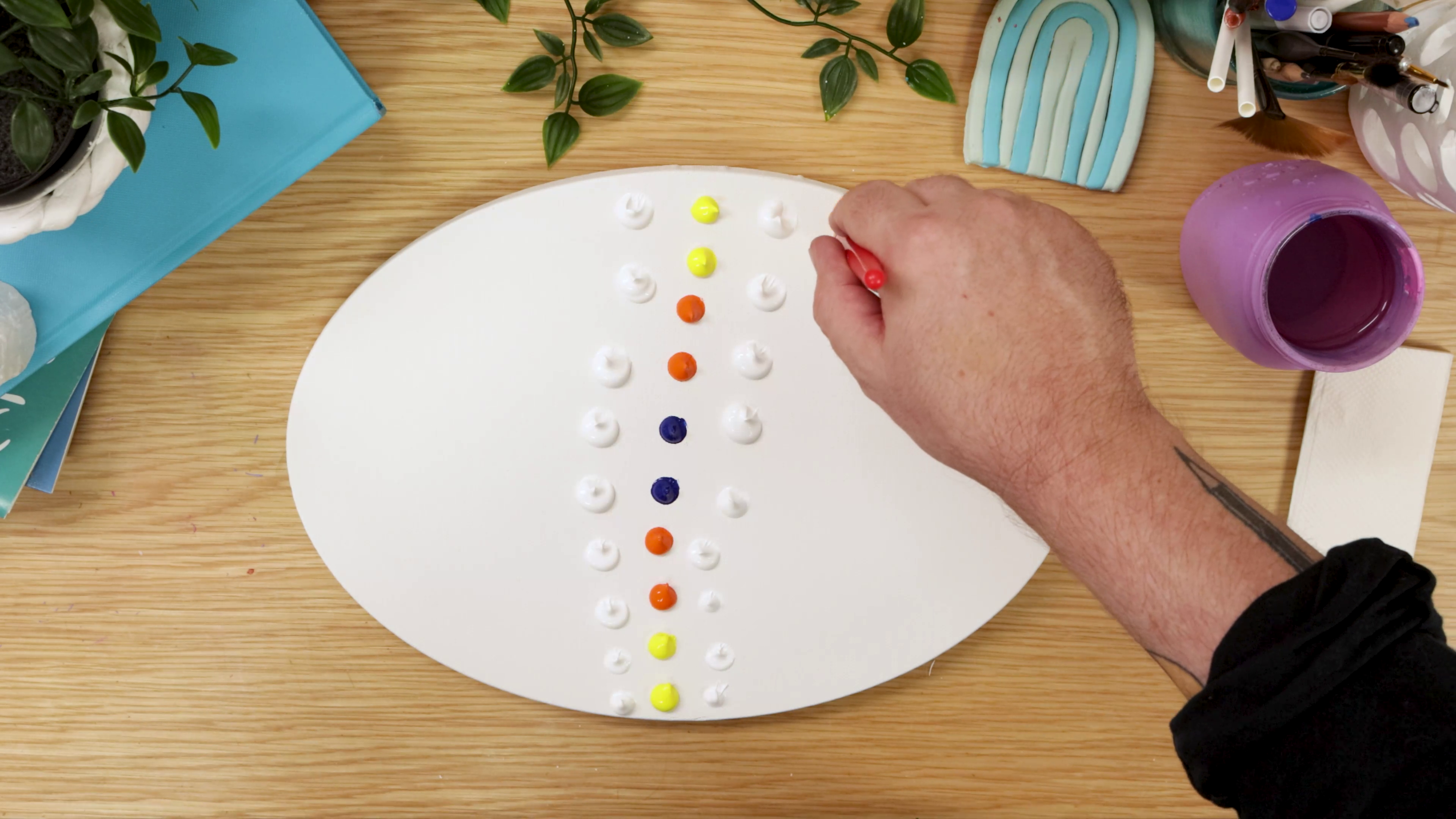 Dots of acrylic colour in a line on oval canvas