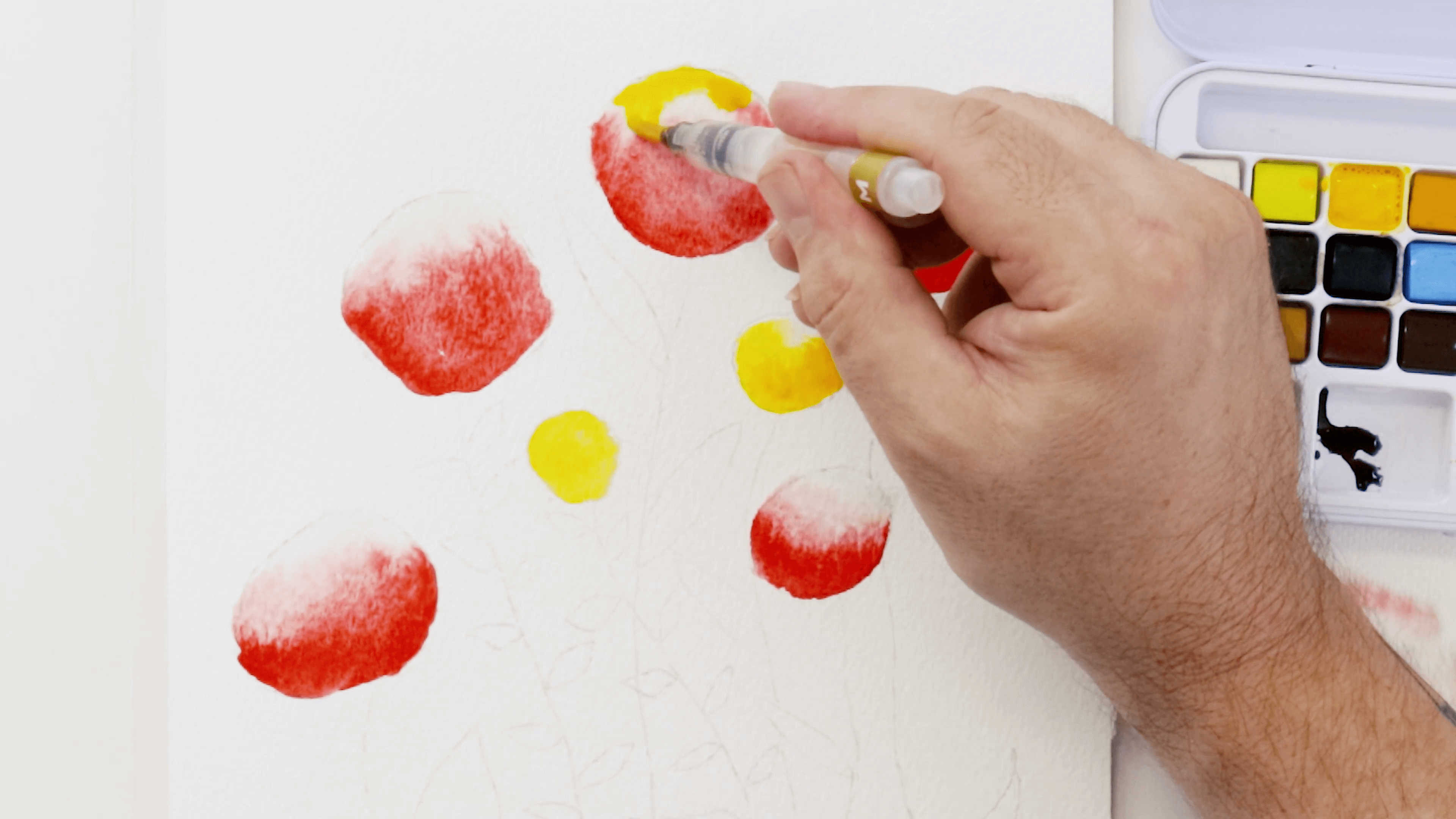 A hand holding a watercolour brush adds the colour medium yellow to the flower bud drawing.