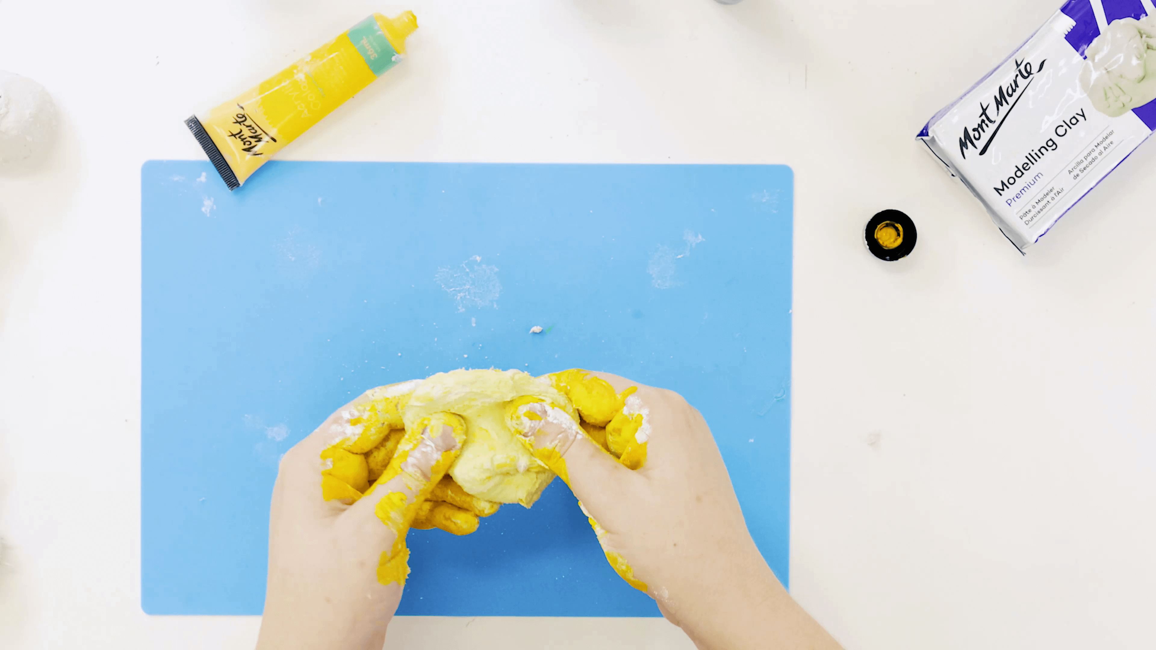 Hand kneading the yellow acrylic colour into a clay ball