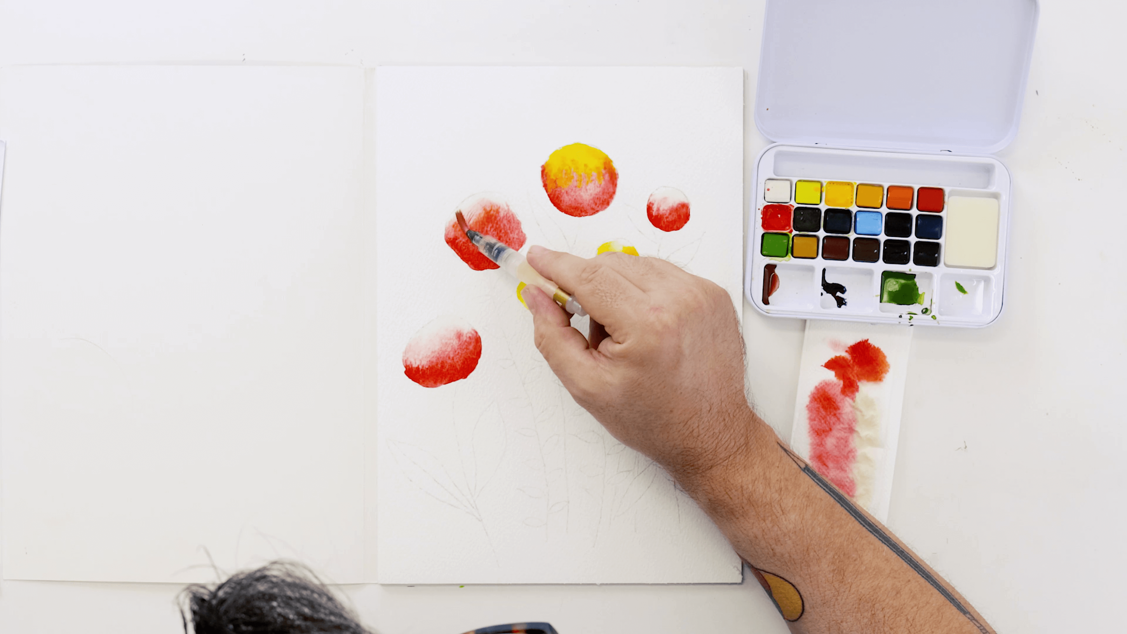 A hand holding a watercolour brush adds the colour Sorbet to darken the flowers.