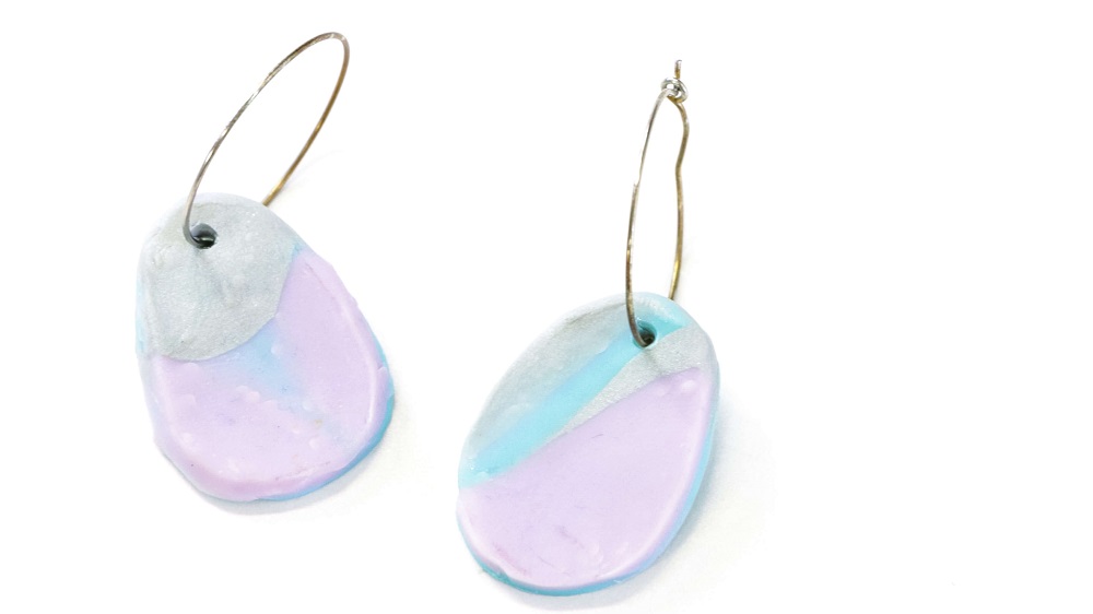 A pair of two polymer clay earrings with a blue, lilac and silver marble design and a small gold hoop for each.