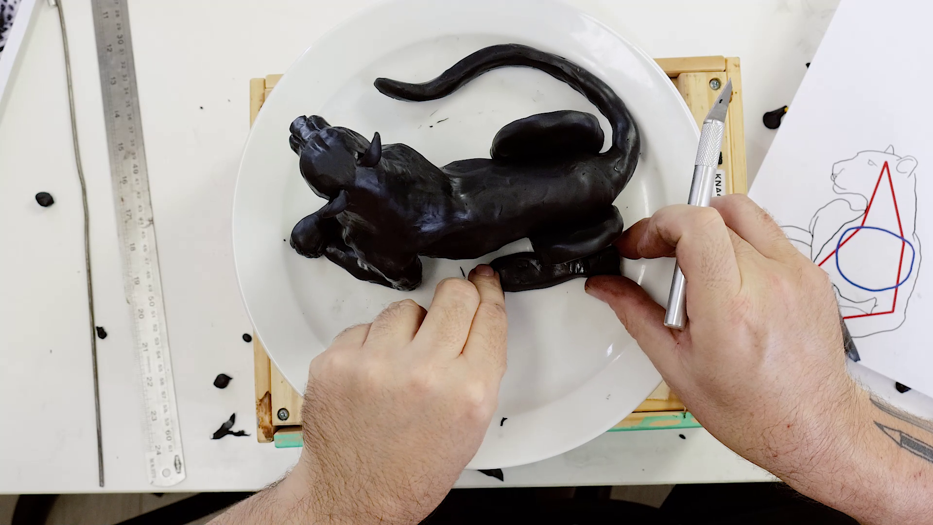 Sculpting the hind legs with black polymer clay and a precision knife