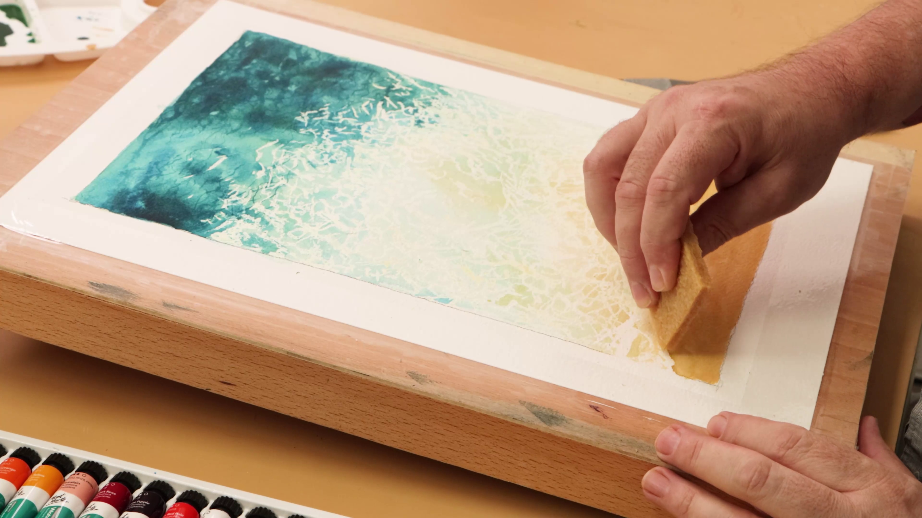 Adhesive eraser removing masking fluid from beach scene