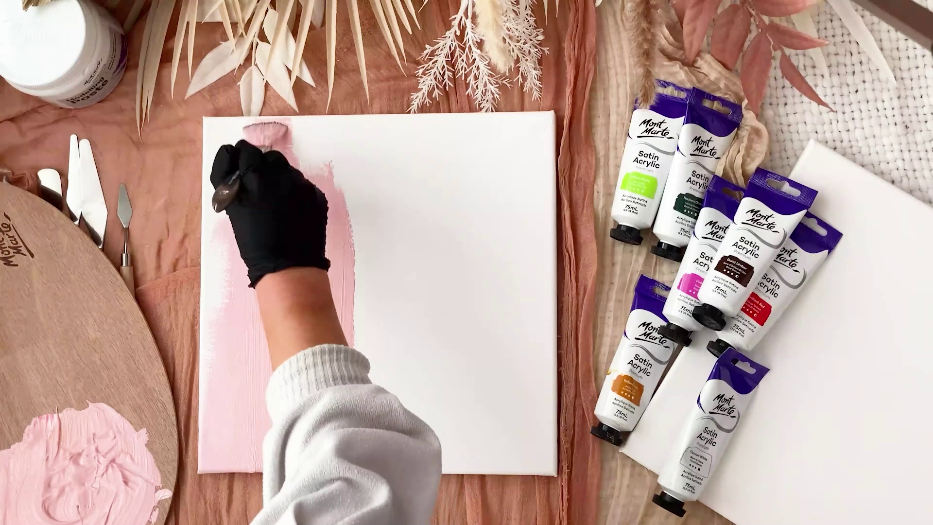 Gloved hand painting background pink tone on white canvas