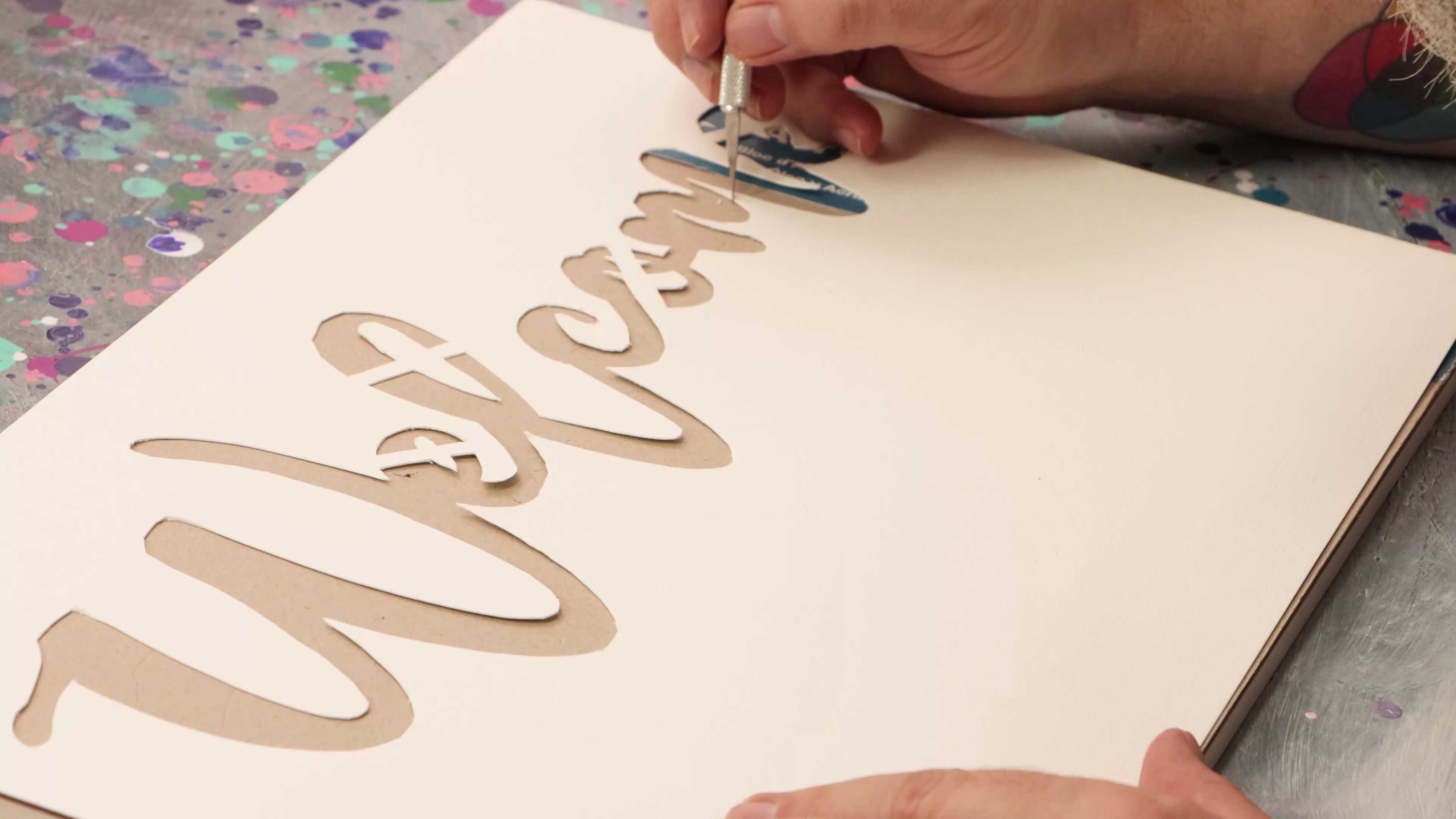 Welcome paper stencil being cut with a craft knife