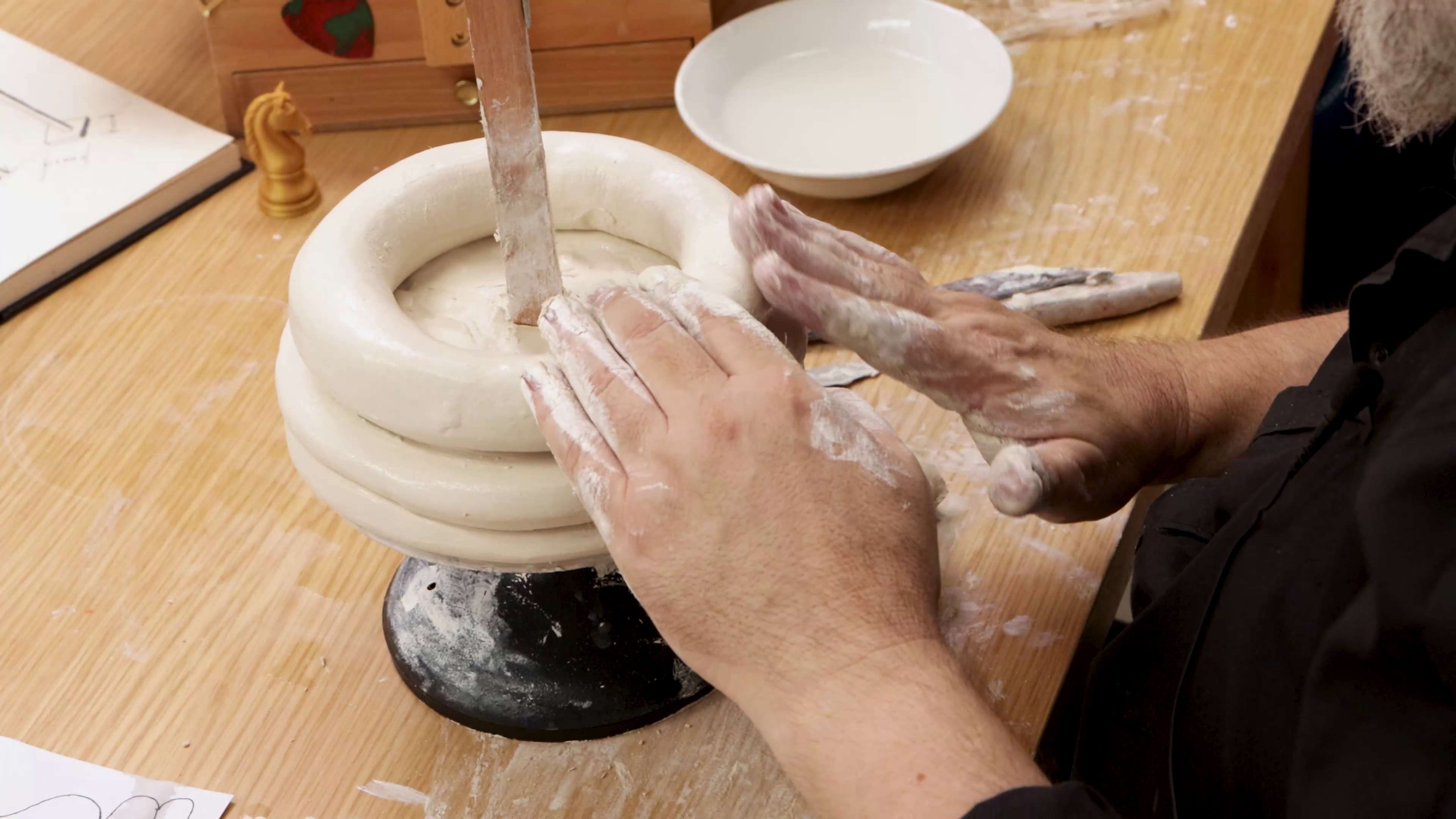 Rings of clay build on top of armature on wheel