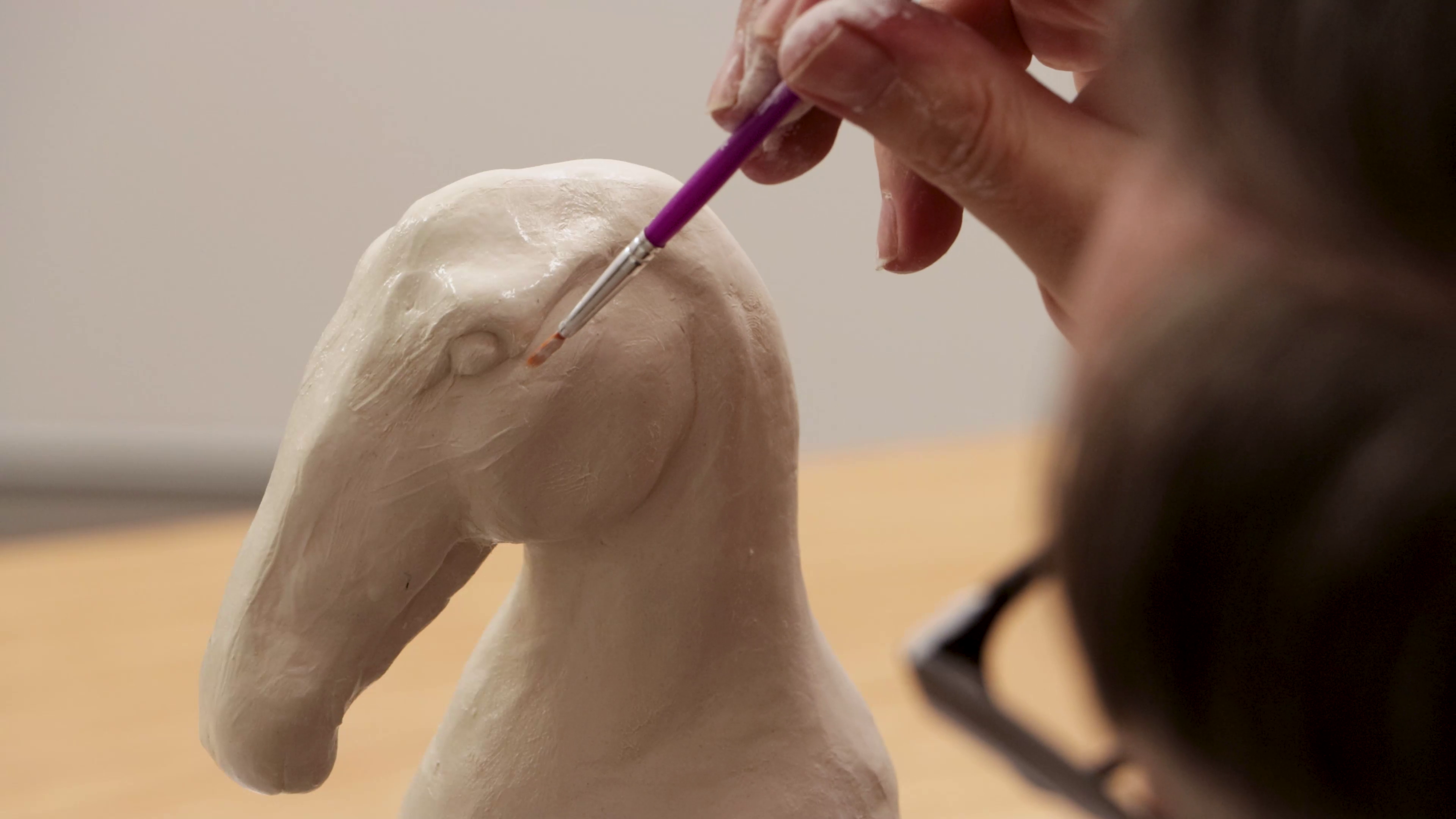 Brush refining eye shape on horse clay sculpture