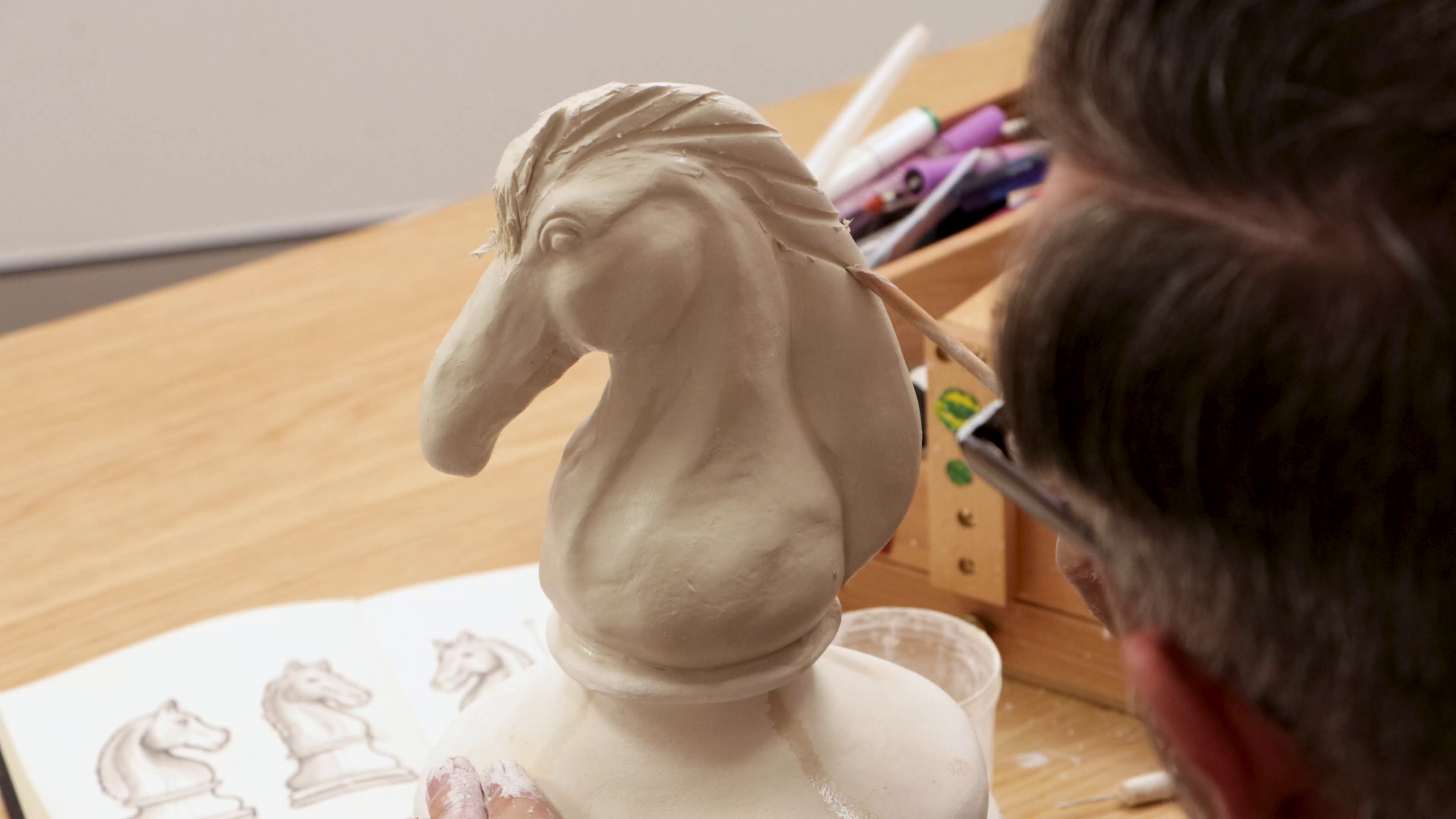 Carving hair lines into clay horse mane
