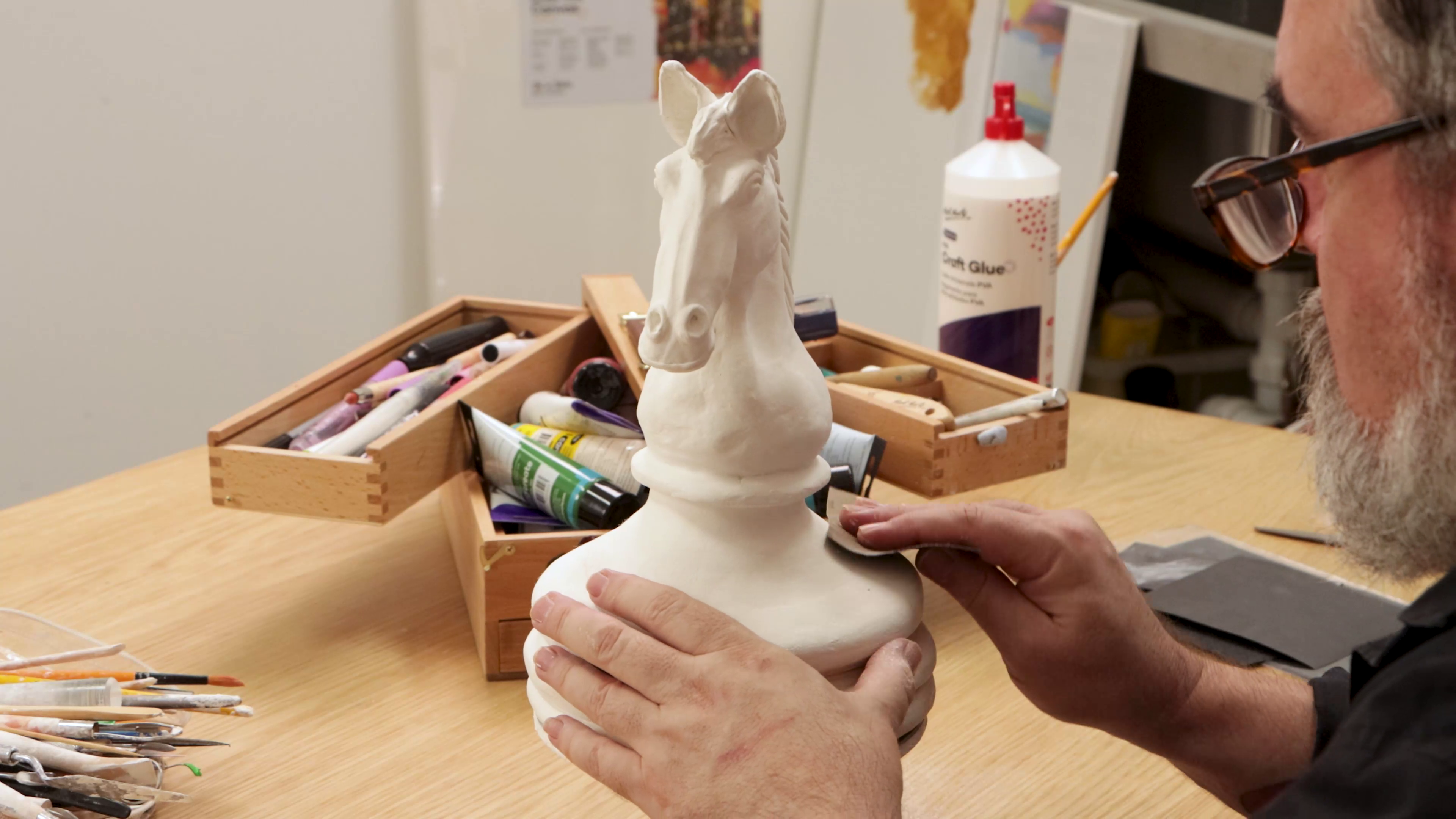 Artist sanding clay chess knight sculpture