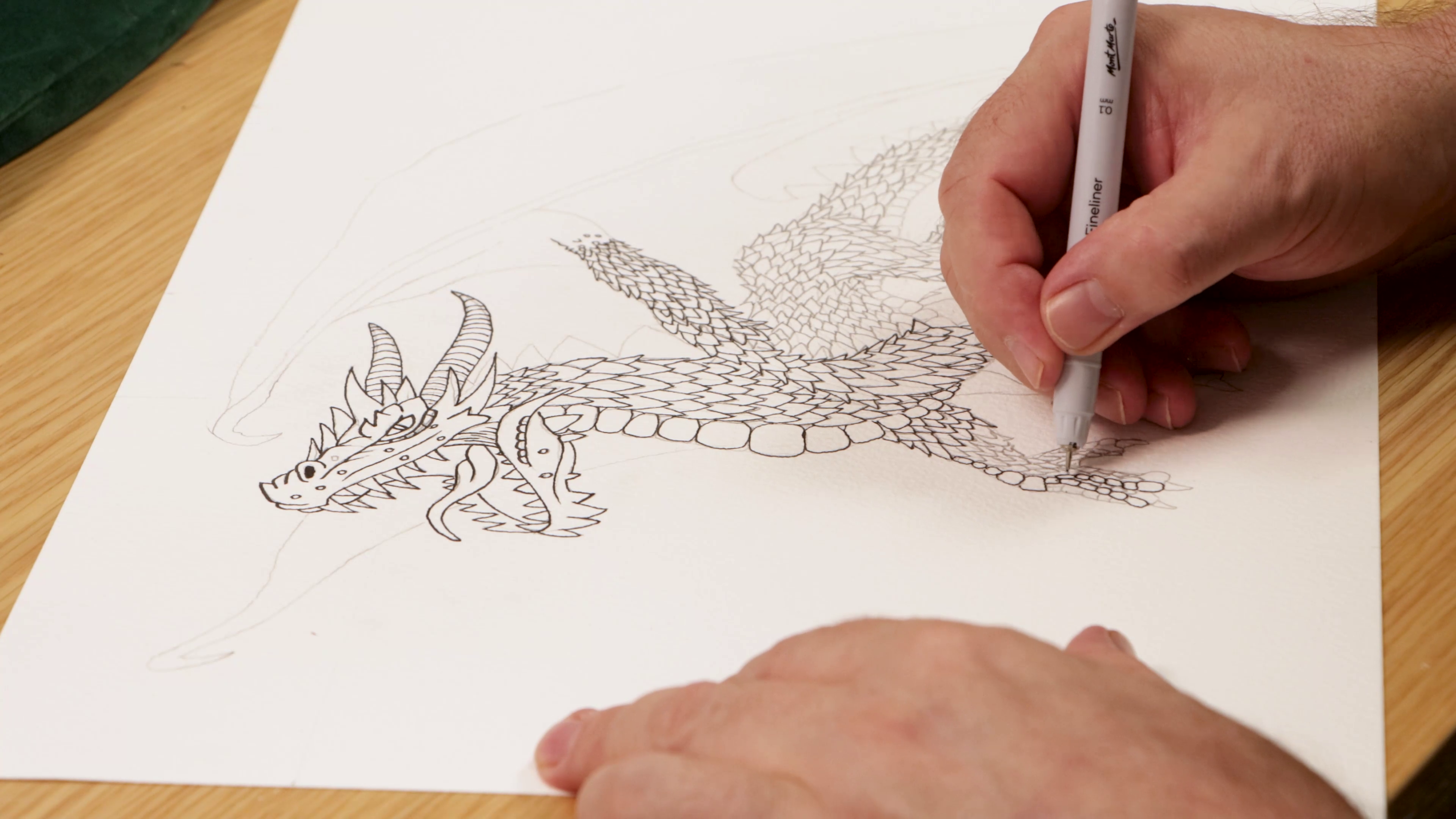 Outlining dragon drawing in pen