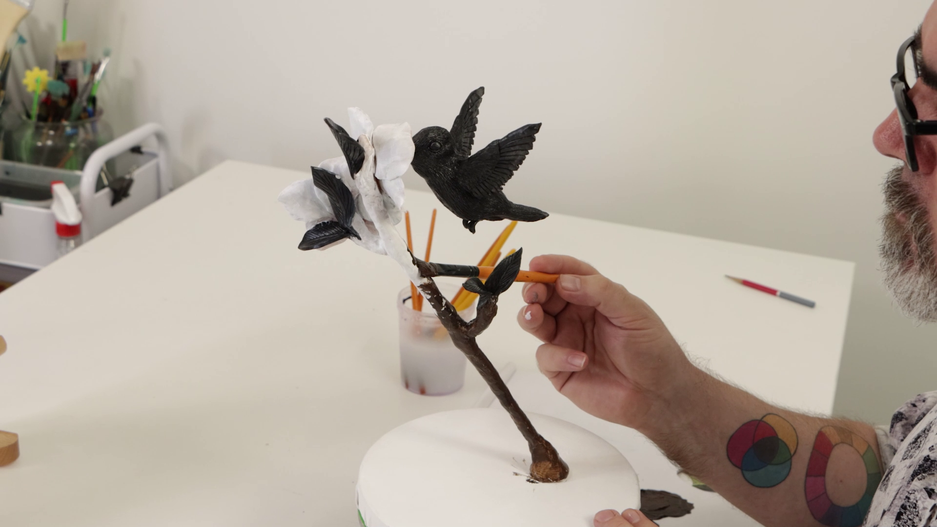 Hummingbird and flower branch sculpture being painted with black and white base coat