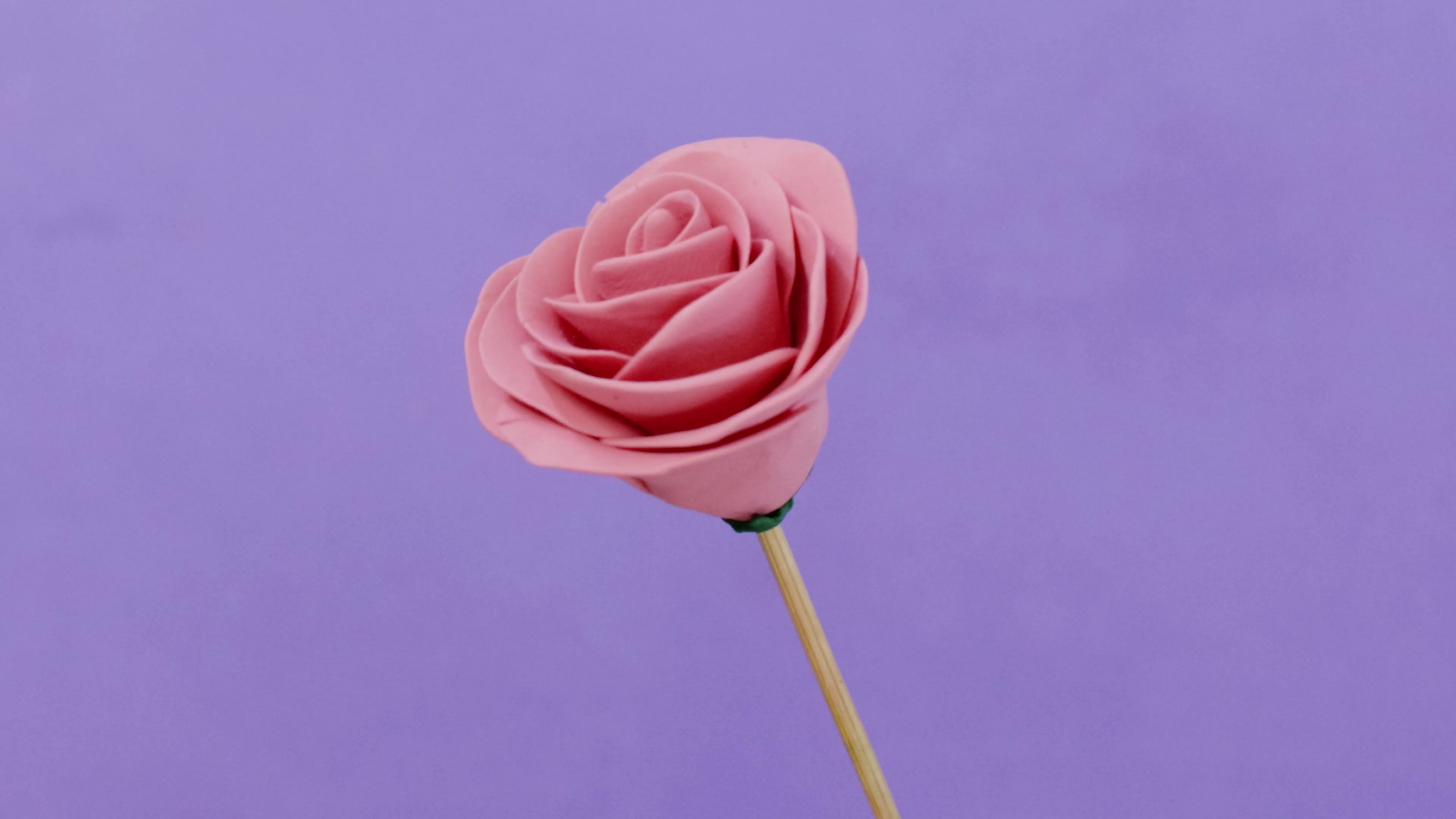 Pink polymer clay rose sculpted on a skewer