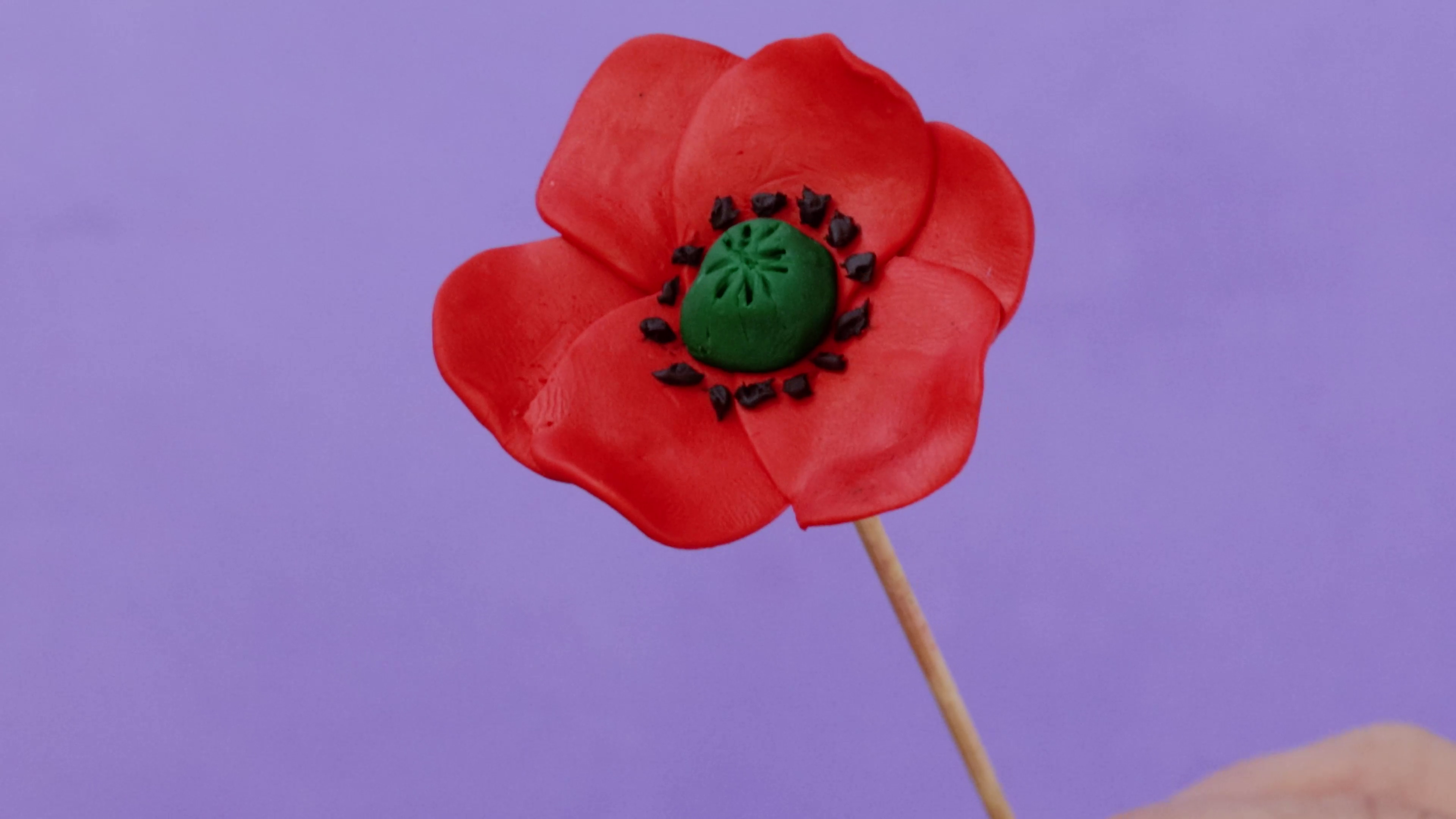 Pink polymer clay poppy sculpted on a skewer