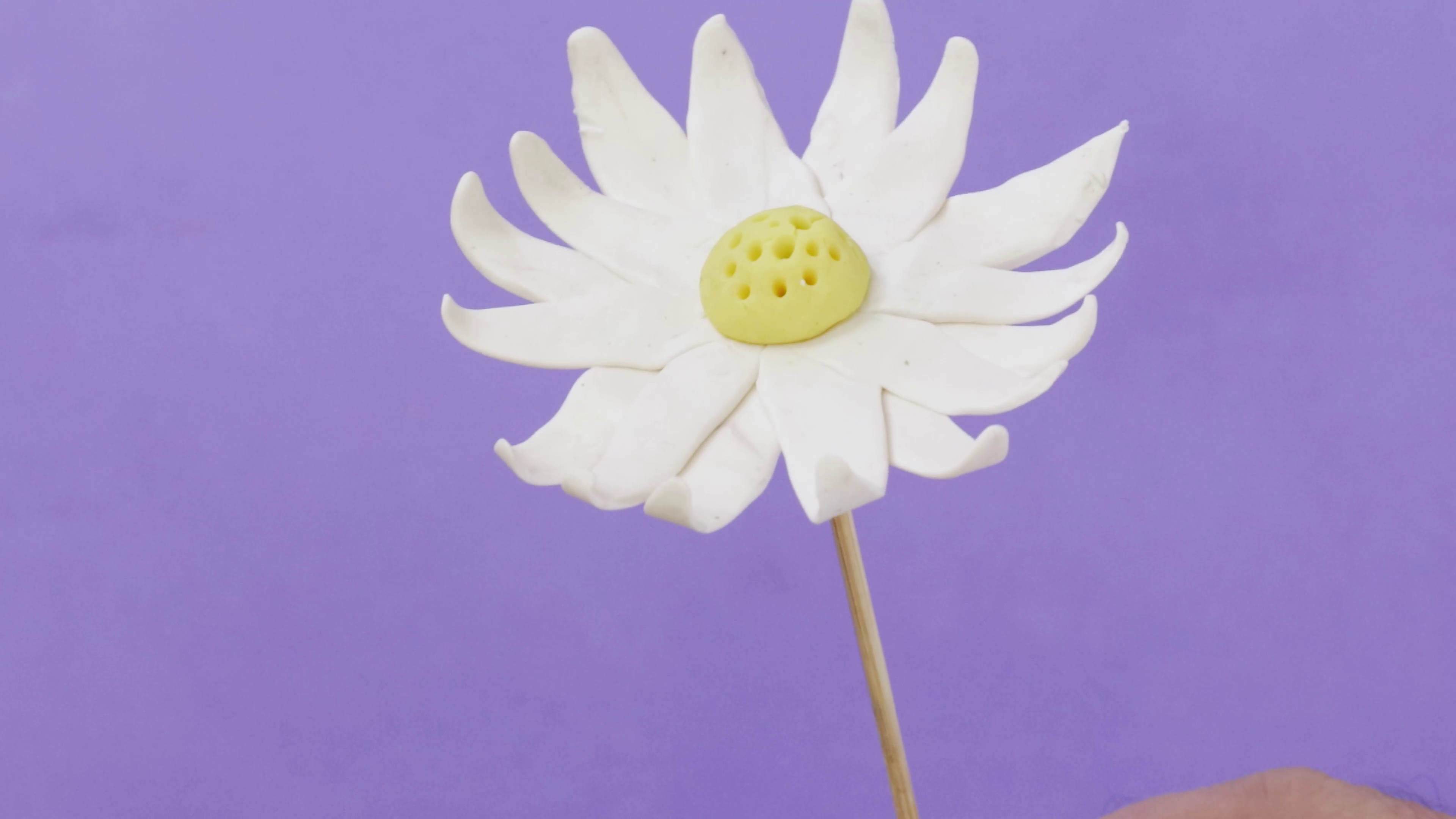 Pink polymer clay daisy sculpted on a skewer