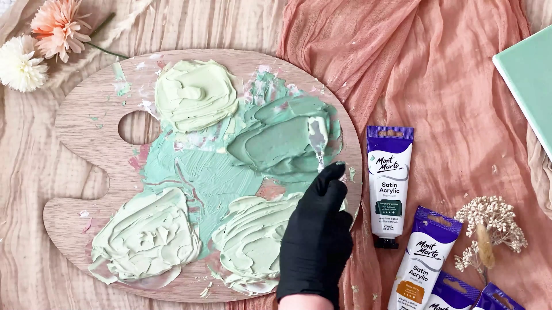 Light moulding paste mixed with different green shades on wood palette