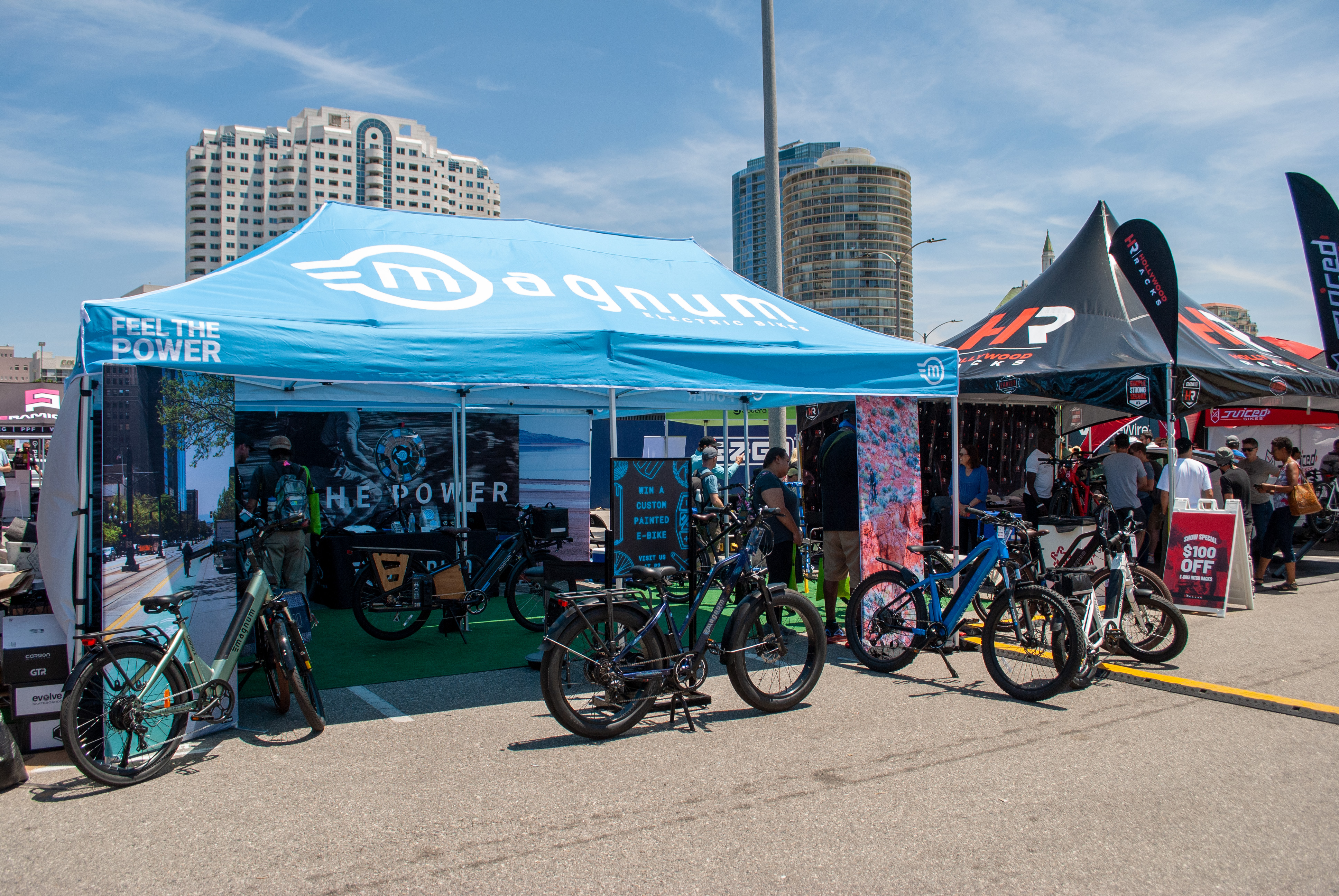 Blue Magnum Bikes tent outdoors in the sun with electric bikes displayed