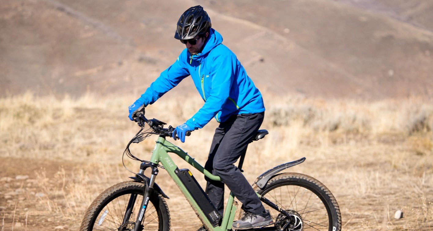 Rider with bright blue jacket and black jeans riding Magnum Peak T5 across dead grass landscape