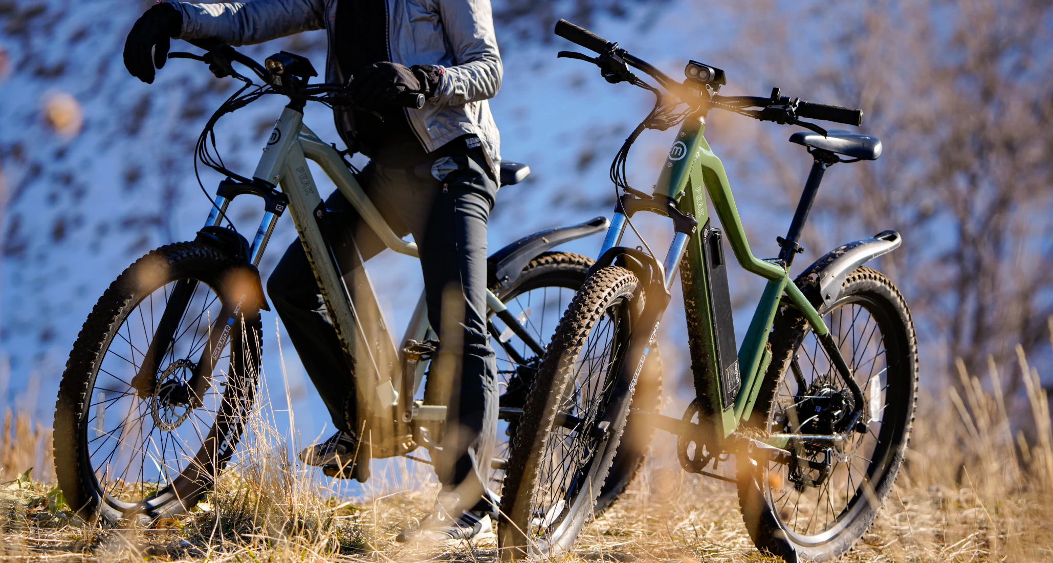 Rider with gray jacket and black pants on Magnum Peak e-bike with dry grass in foreground