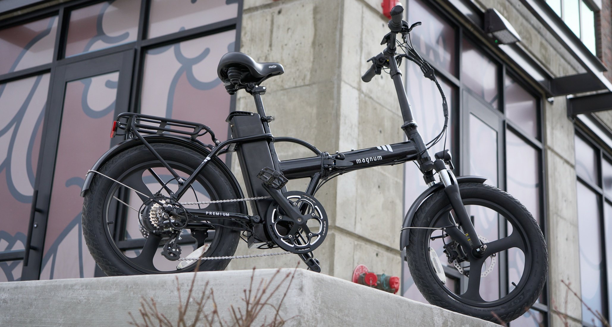 Black Magnum Premium 3 High Step folding bike parked on sidewalk