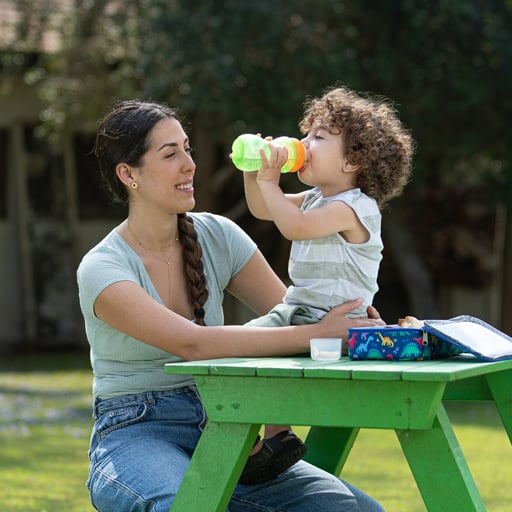 Child drinks from sippy cup outdoors