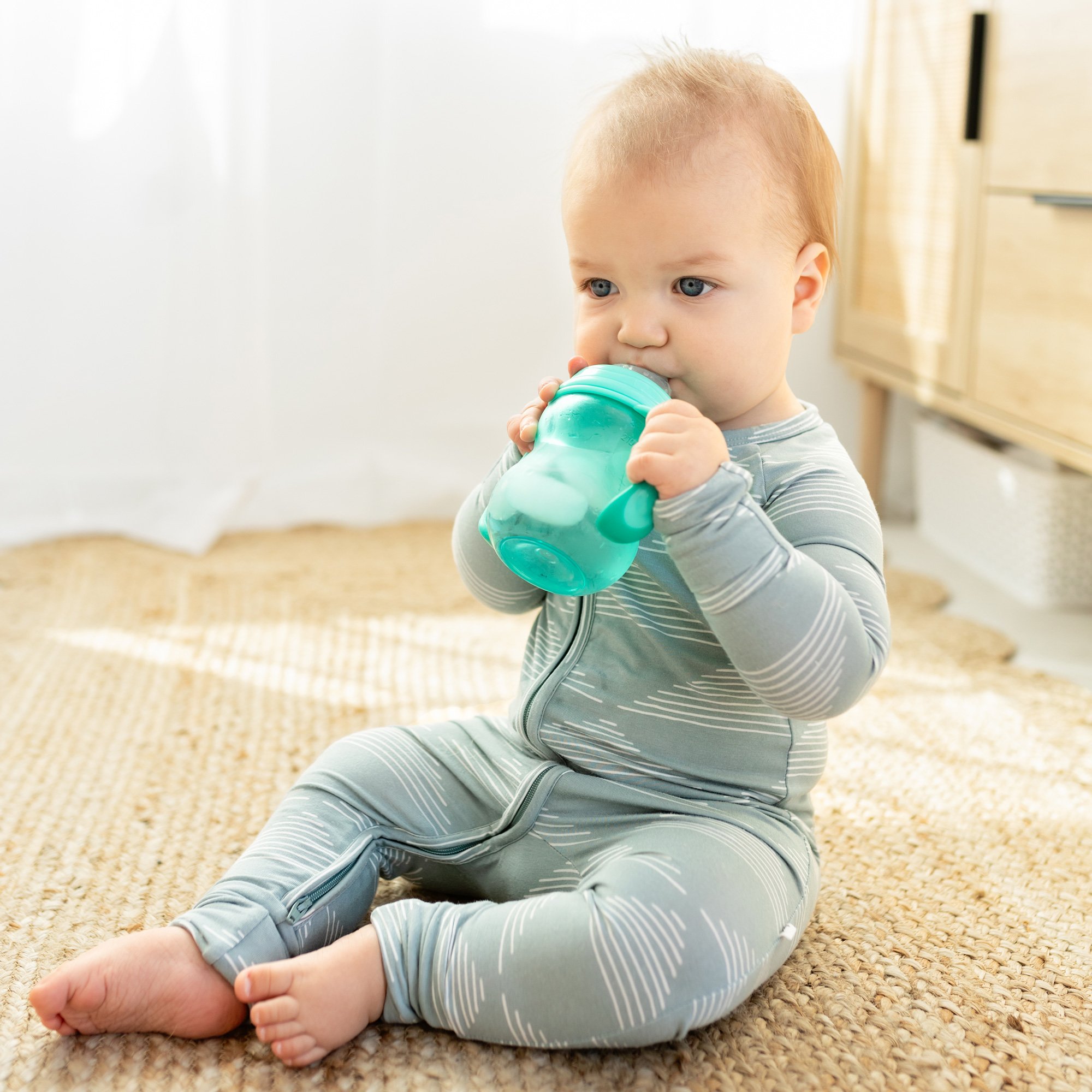 baby drinking from cup on floor