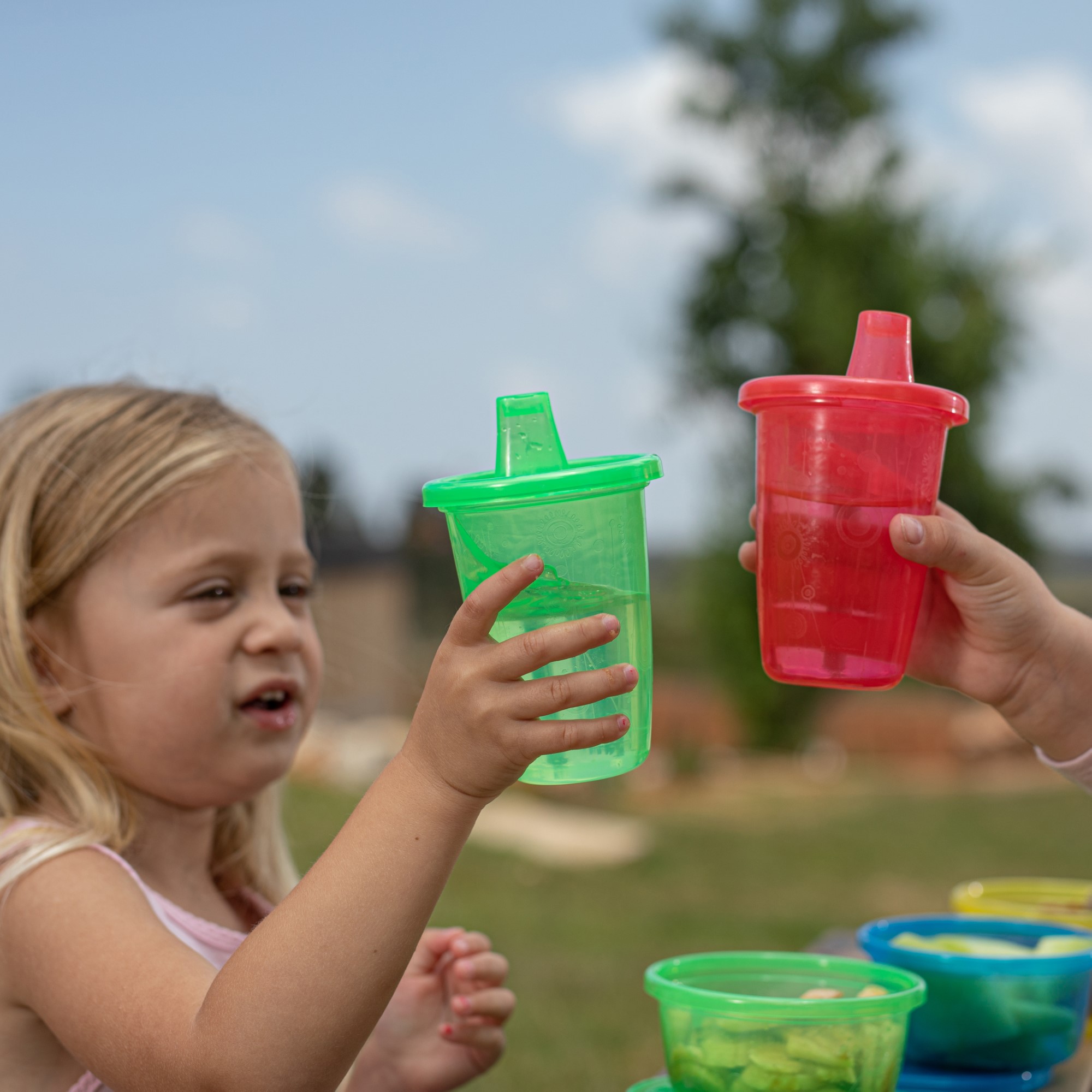Kids clinking two plastic sippy cups together
