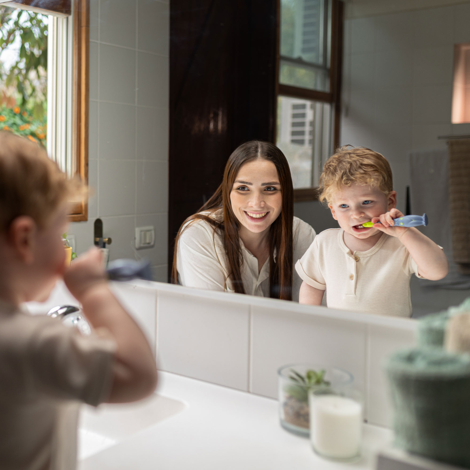 Boy brushing his teeth with his mom