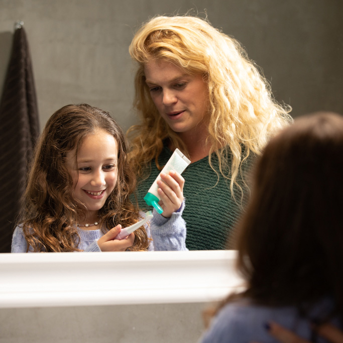 Girl brushing teeth with mom