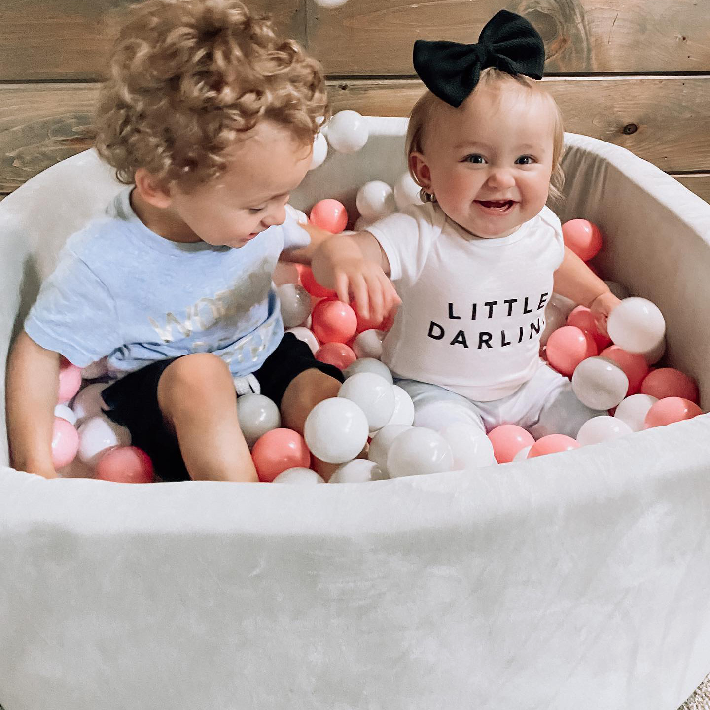 Toddler and baby playing in a ball pit
