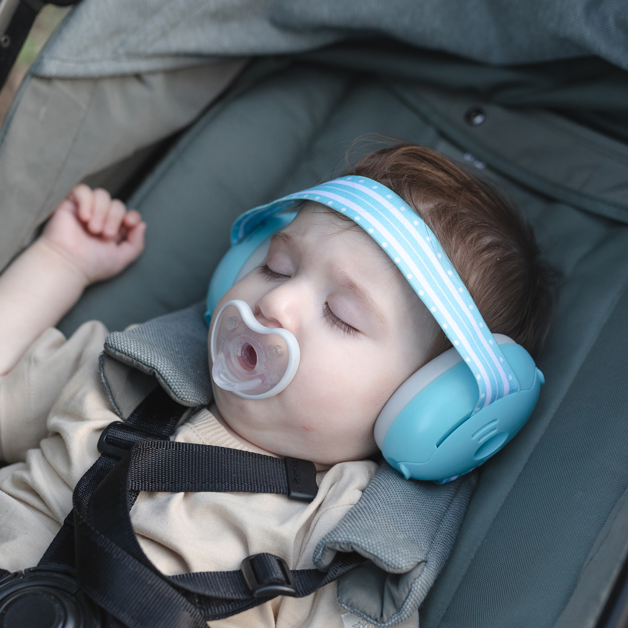 Sleeping baby with pacifier wearing Nuby Soft Sounds Baby Earmuffs.