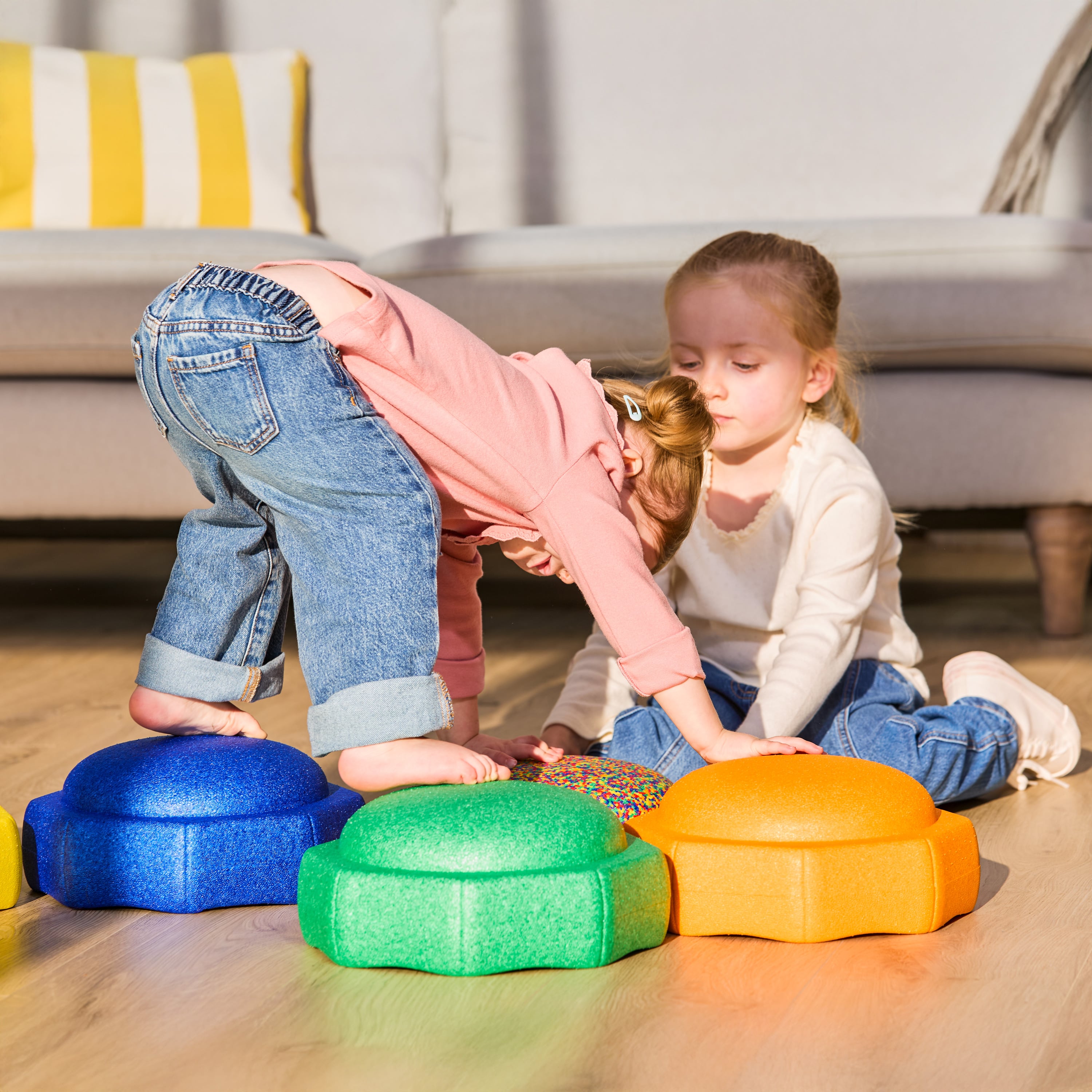 Two children playing with Nuby StepPebble stepping stones, using them to walk across the room on hands and feet while inside.