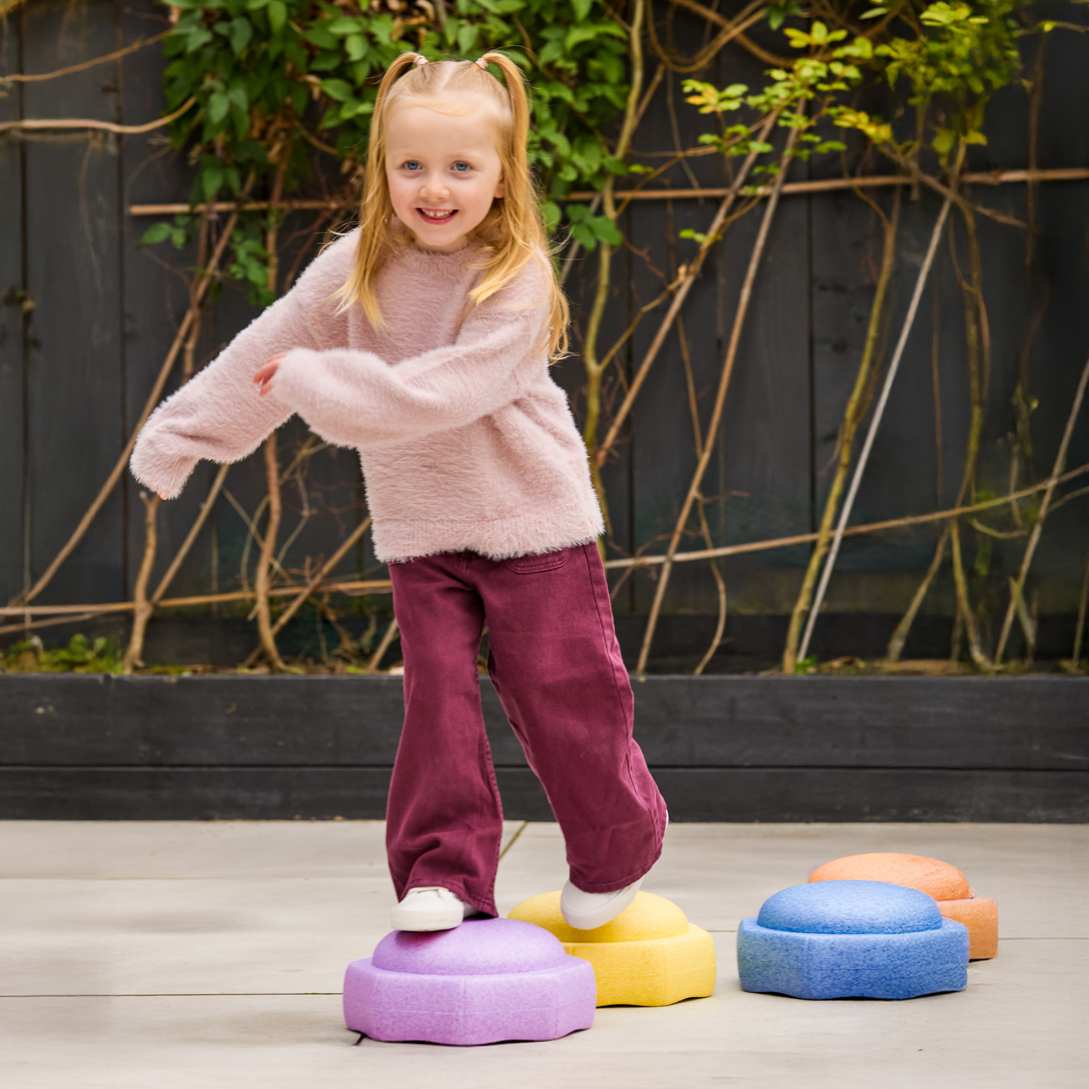 Child hopping across Nuby StepPebble stepping stones, while playing outside.
