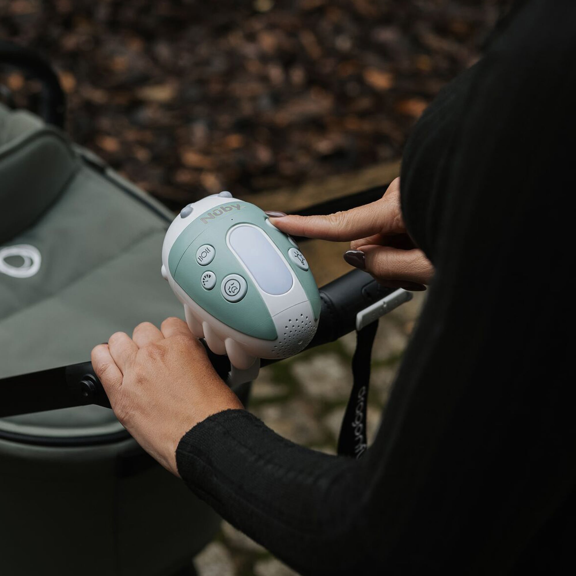 Nuby's Jitterbug stroller rocker in blue-green, on a stroller handle.