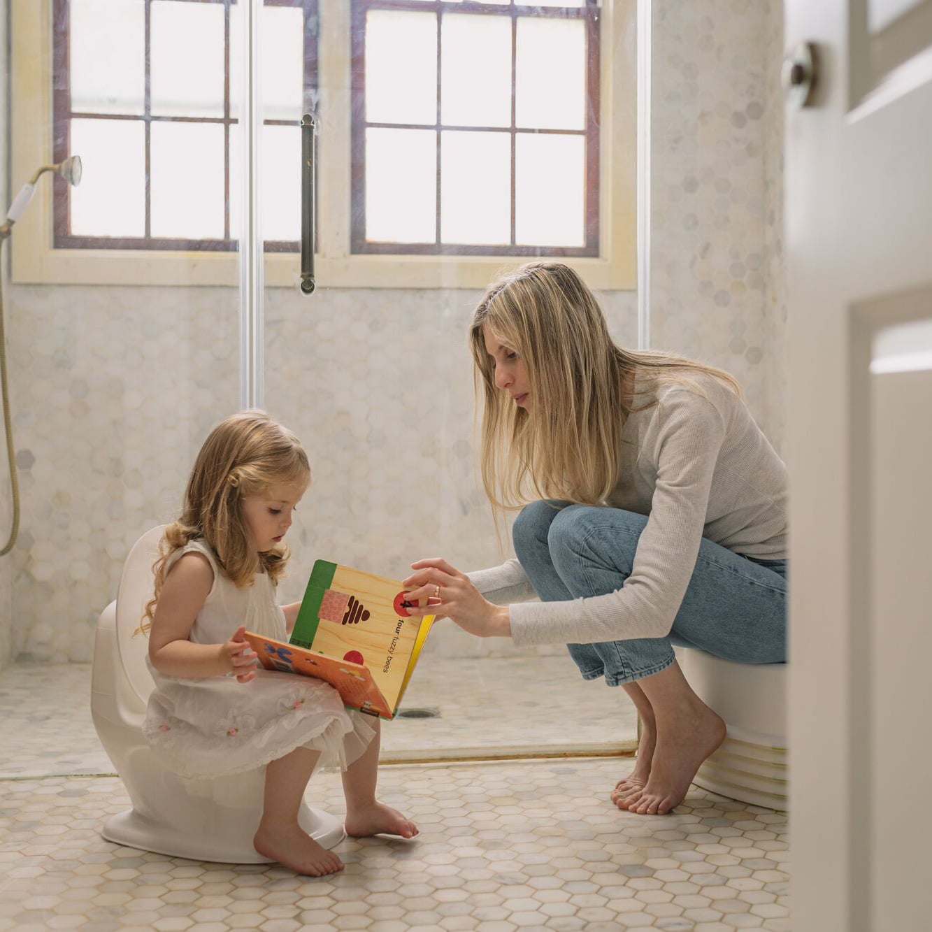 Mother helping toddler learn how to use the My Real Potty from Nuby.