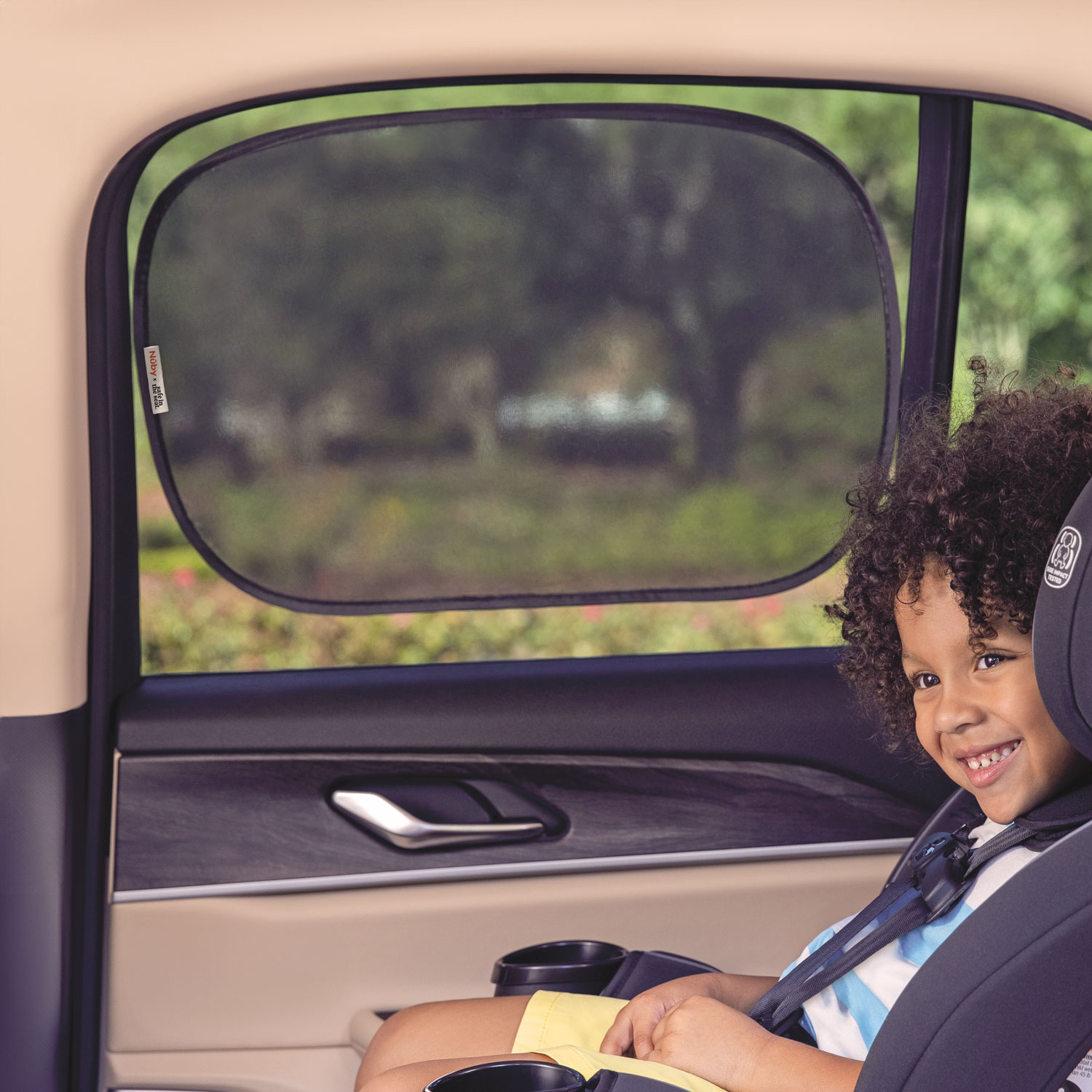 Toddler in forward facing car seat with Nuby x Safe in the Seat window screen.