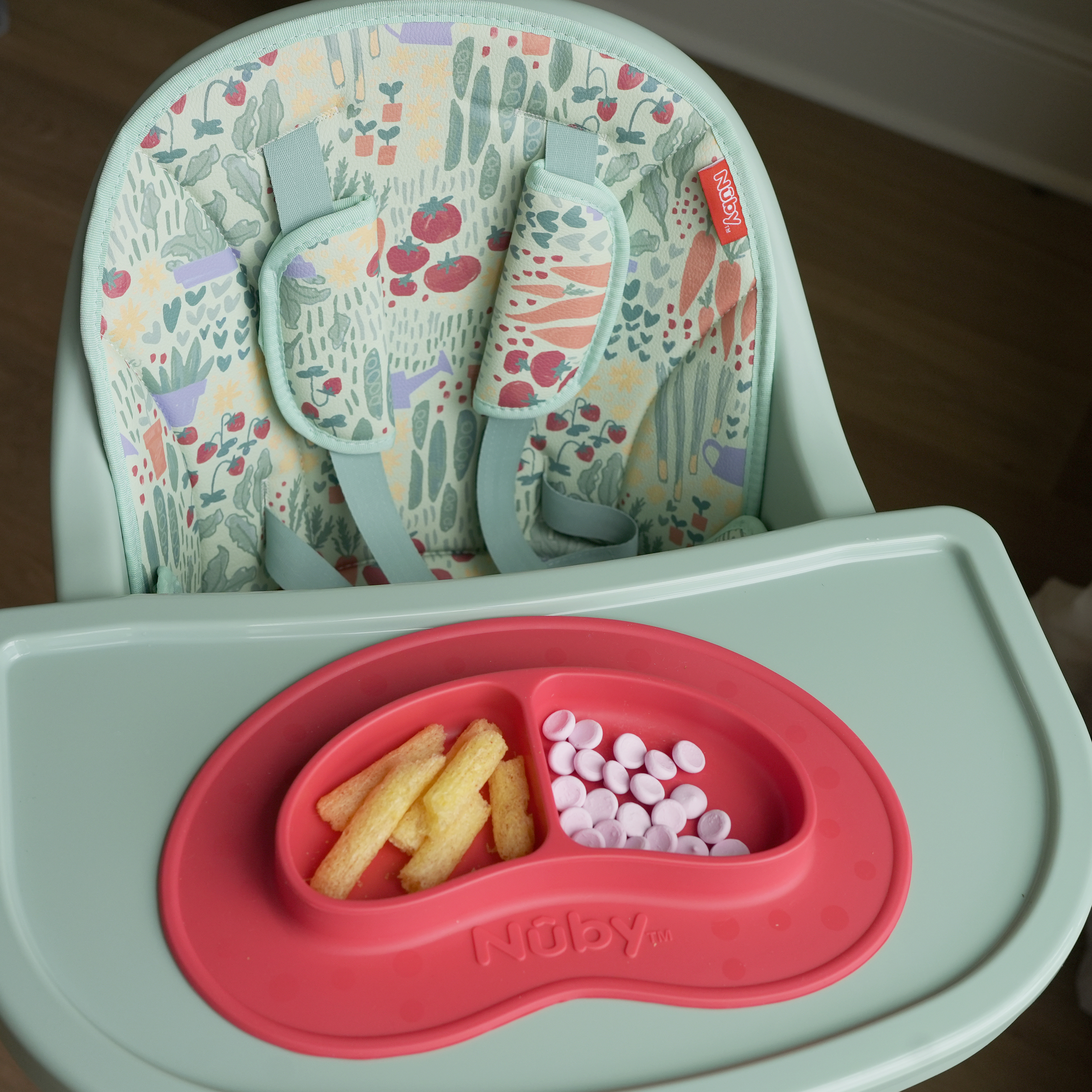 Nuby Green Garden 4-in-1 Multi-Use High Chair with Red Sure Grip Miracle Mat 2-Section Plate on top.