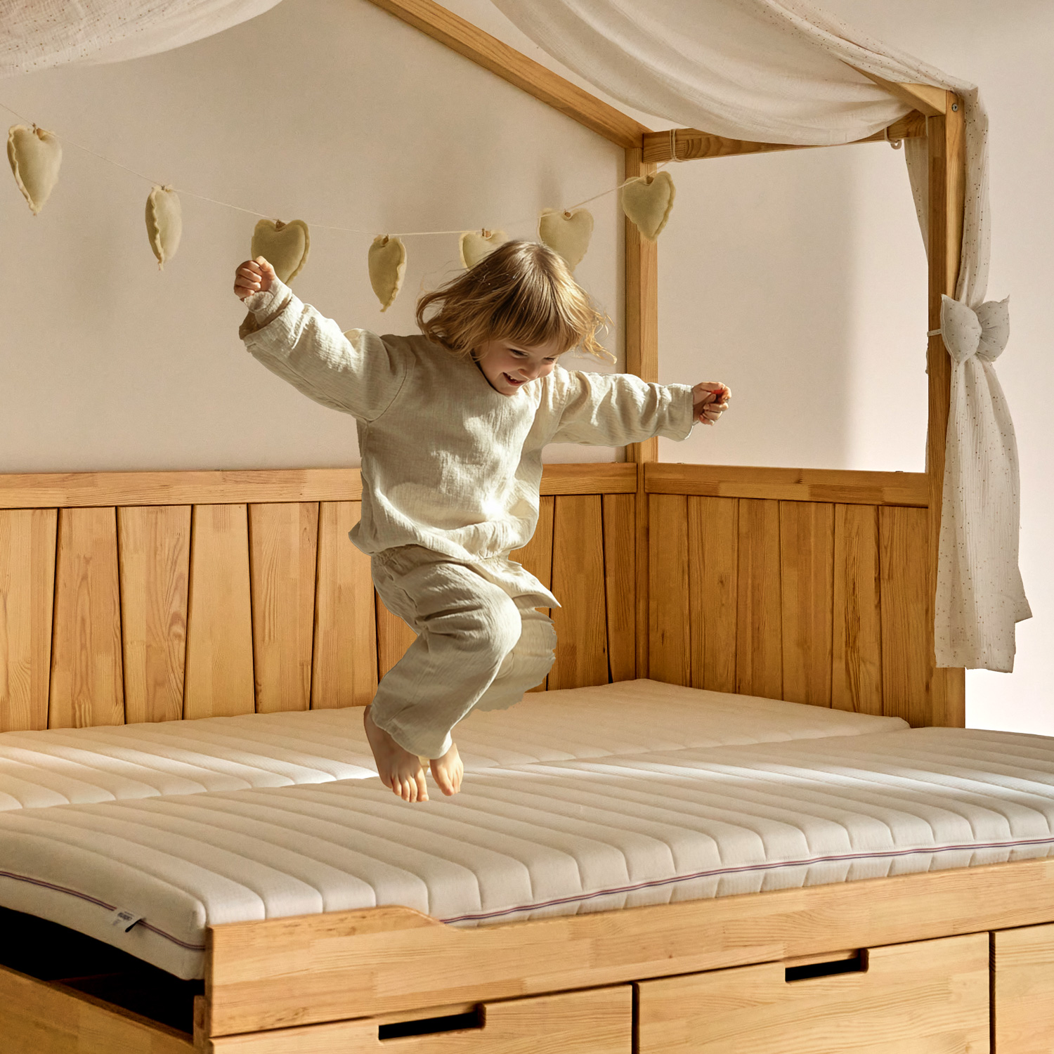 un enfant saute sur un matelas 90 x 190 de lit cabane. Il porte un pantalon beige et un t-shirt blanc. Enfant qui saute sur un lit