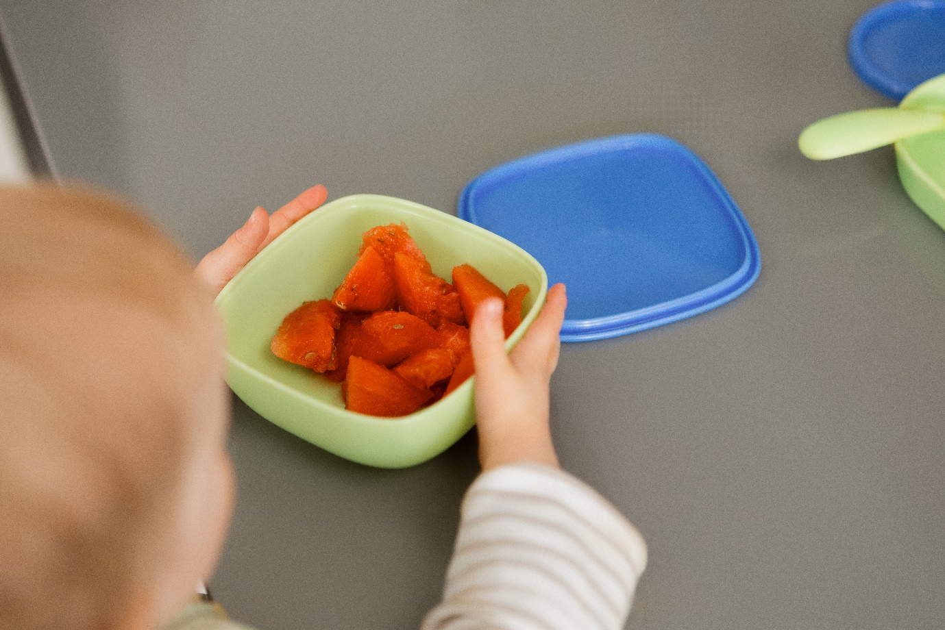 A child holding a bowl of fruitDescription automatically generated