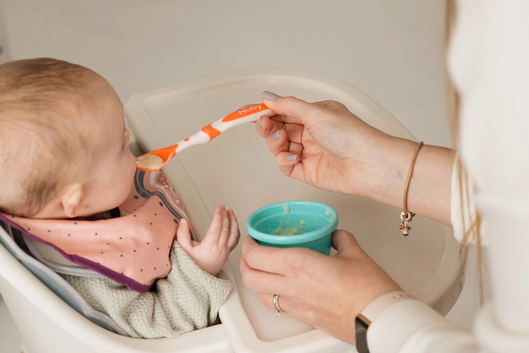 A baby being fed by a spoonDescription automatically generated